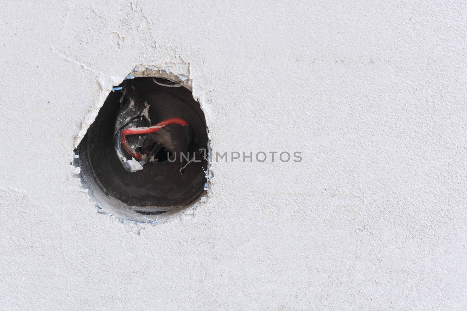 Plastered wall with exposed wires in wall socket 