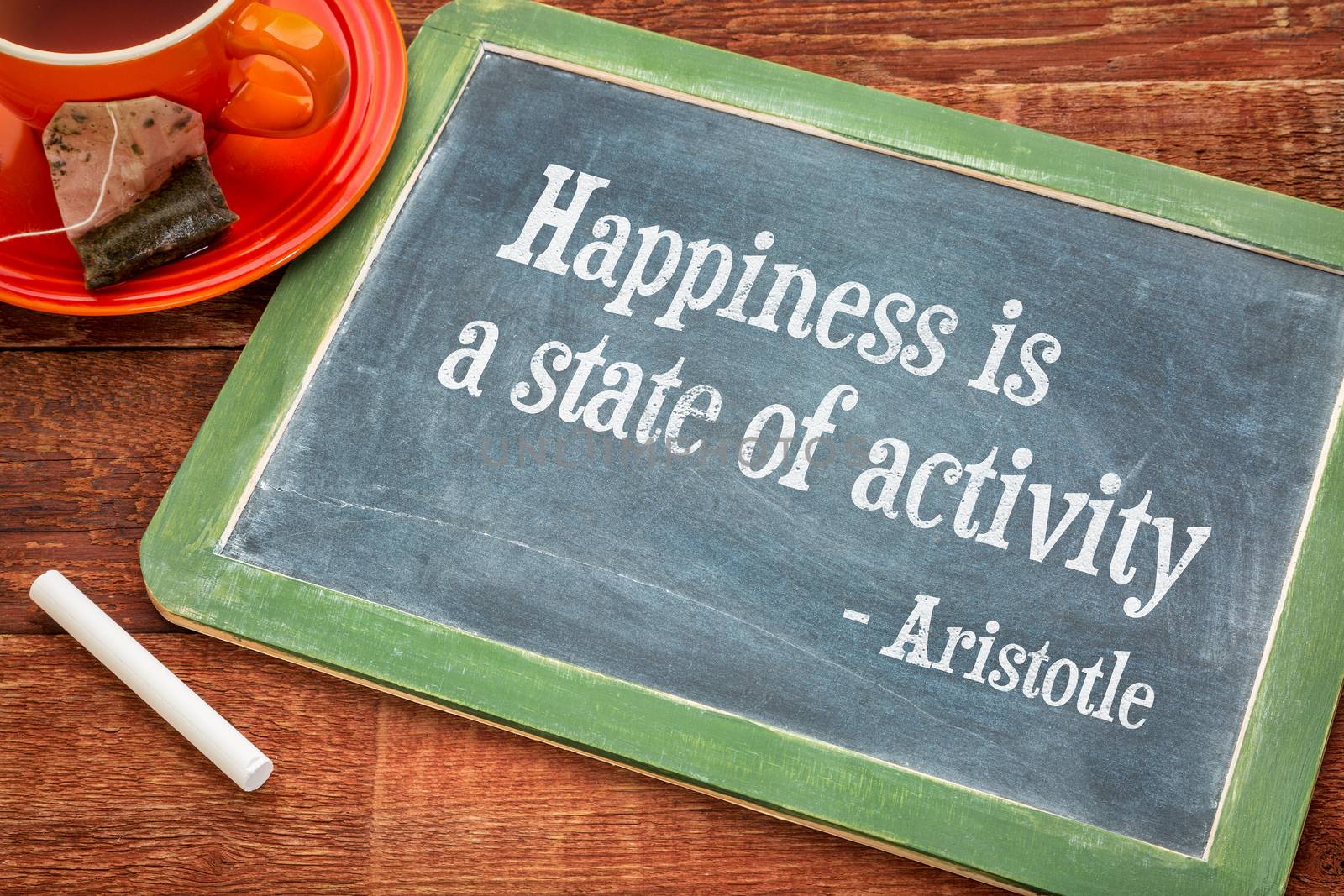 Happiness is a state of activity, a quote from Aristotle - motivational words on a slate blackboard with chalk and cup of tea