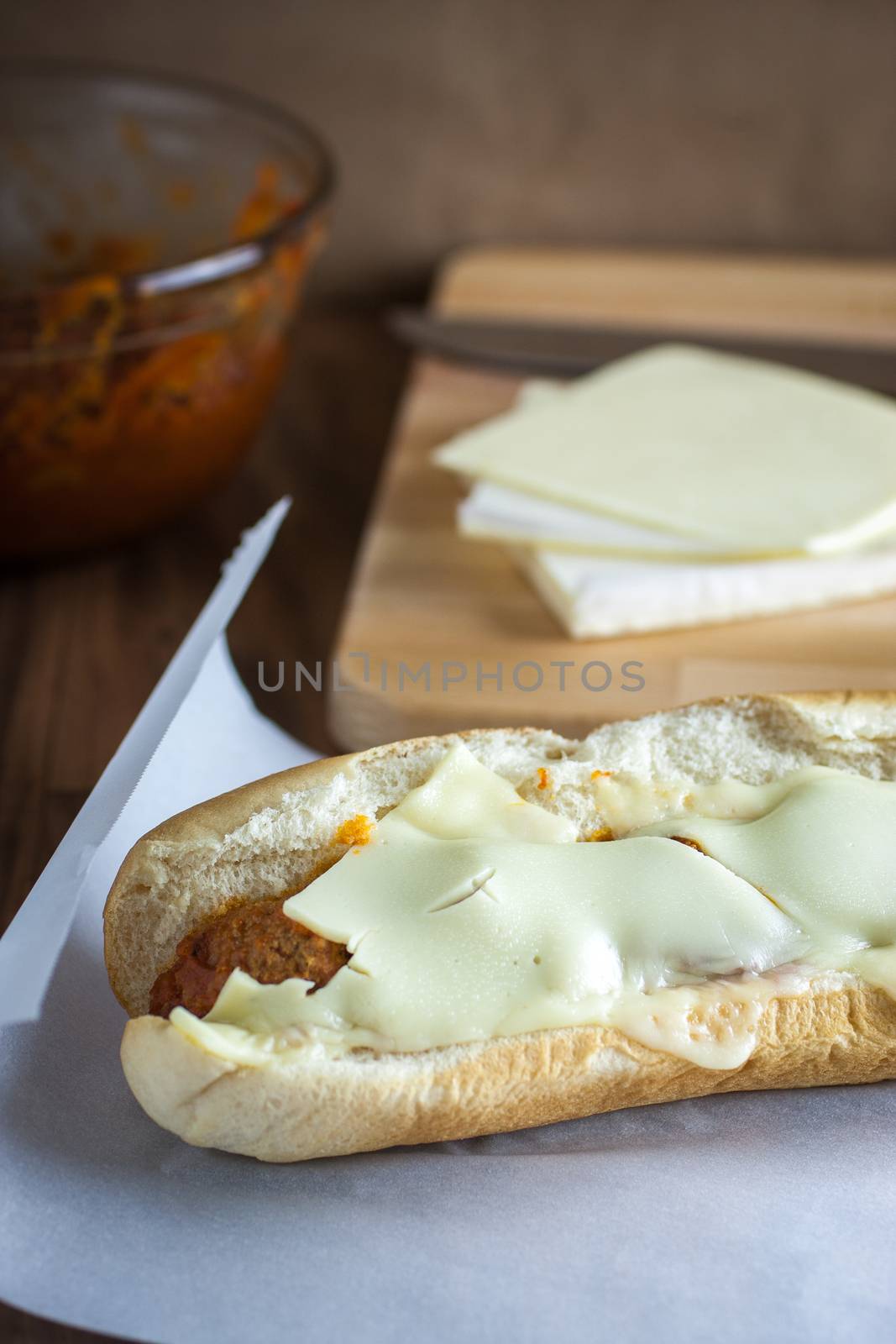 A fresh meatball sandwich with cheese on parchment paper.