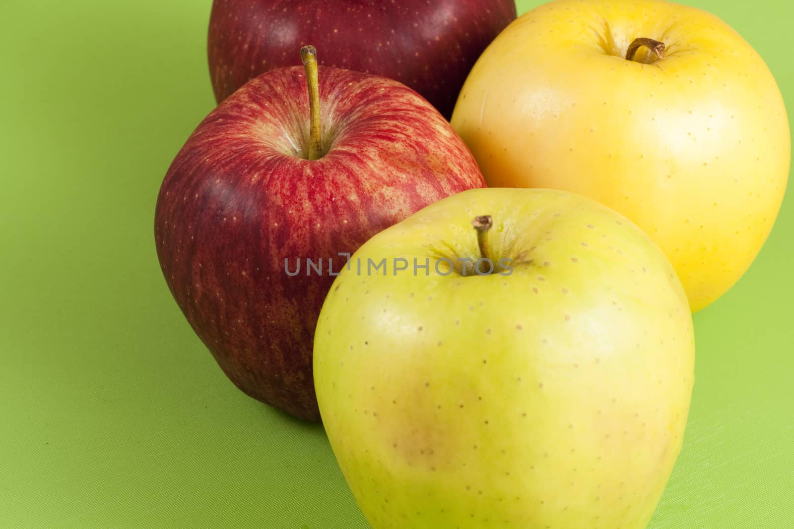 red and green apples on a green floor and a whole pear