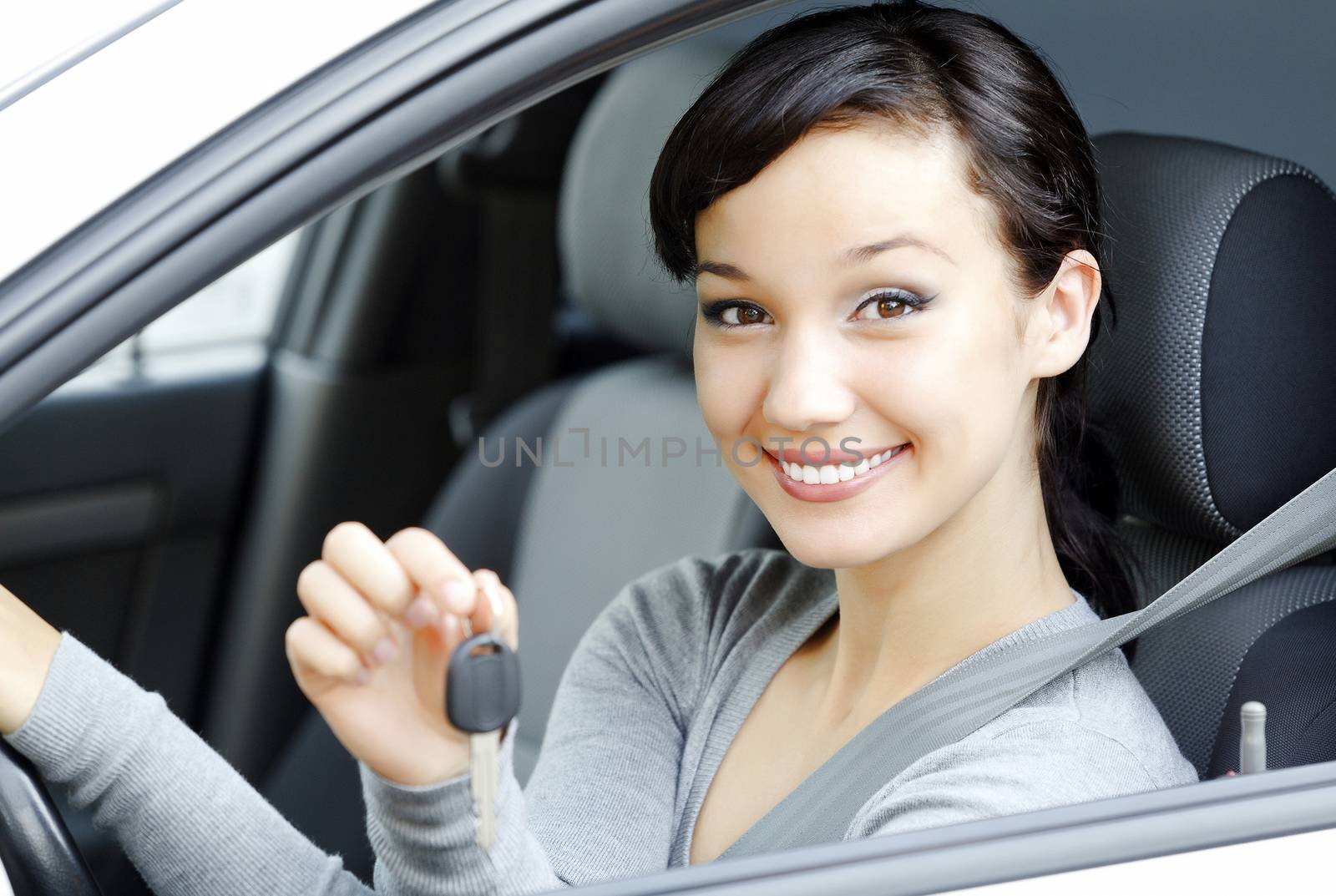 Pretty female driver in a white car showing the car key by Nobilior