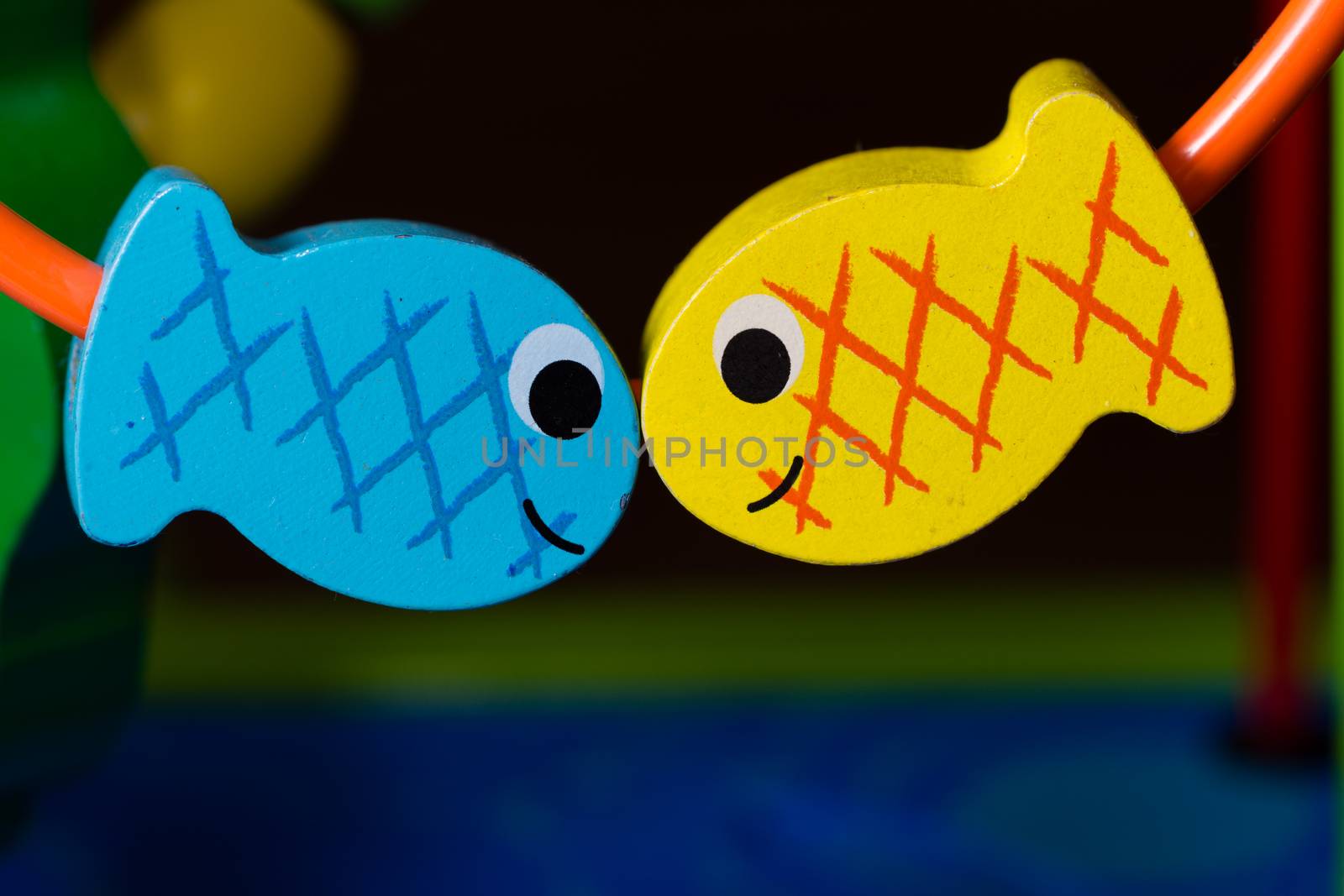 Two colorful toy wooden fish positioned to look like they're kissing.