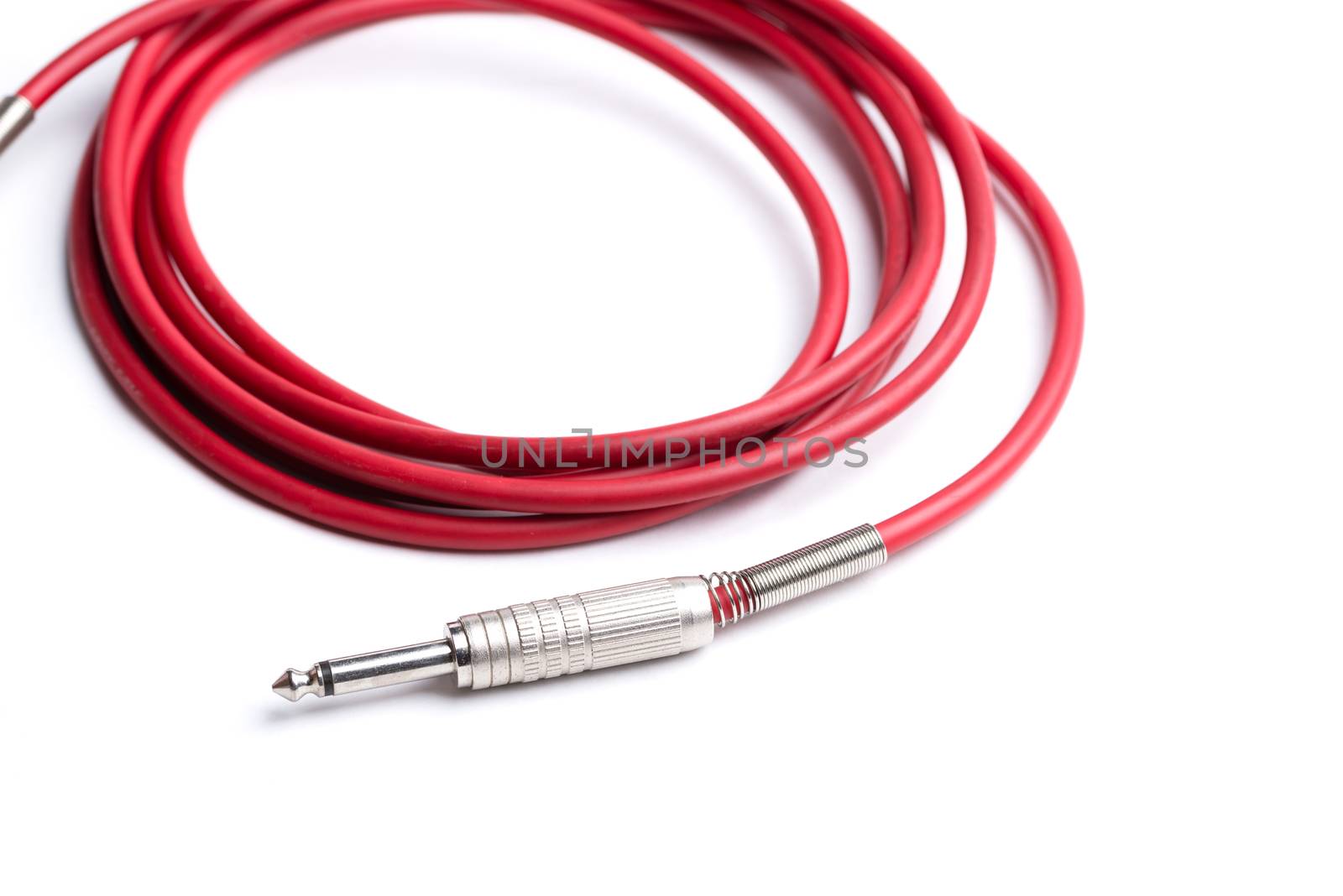 A red quarter inch cable for electric guitar isolated on a white background.