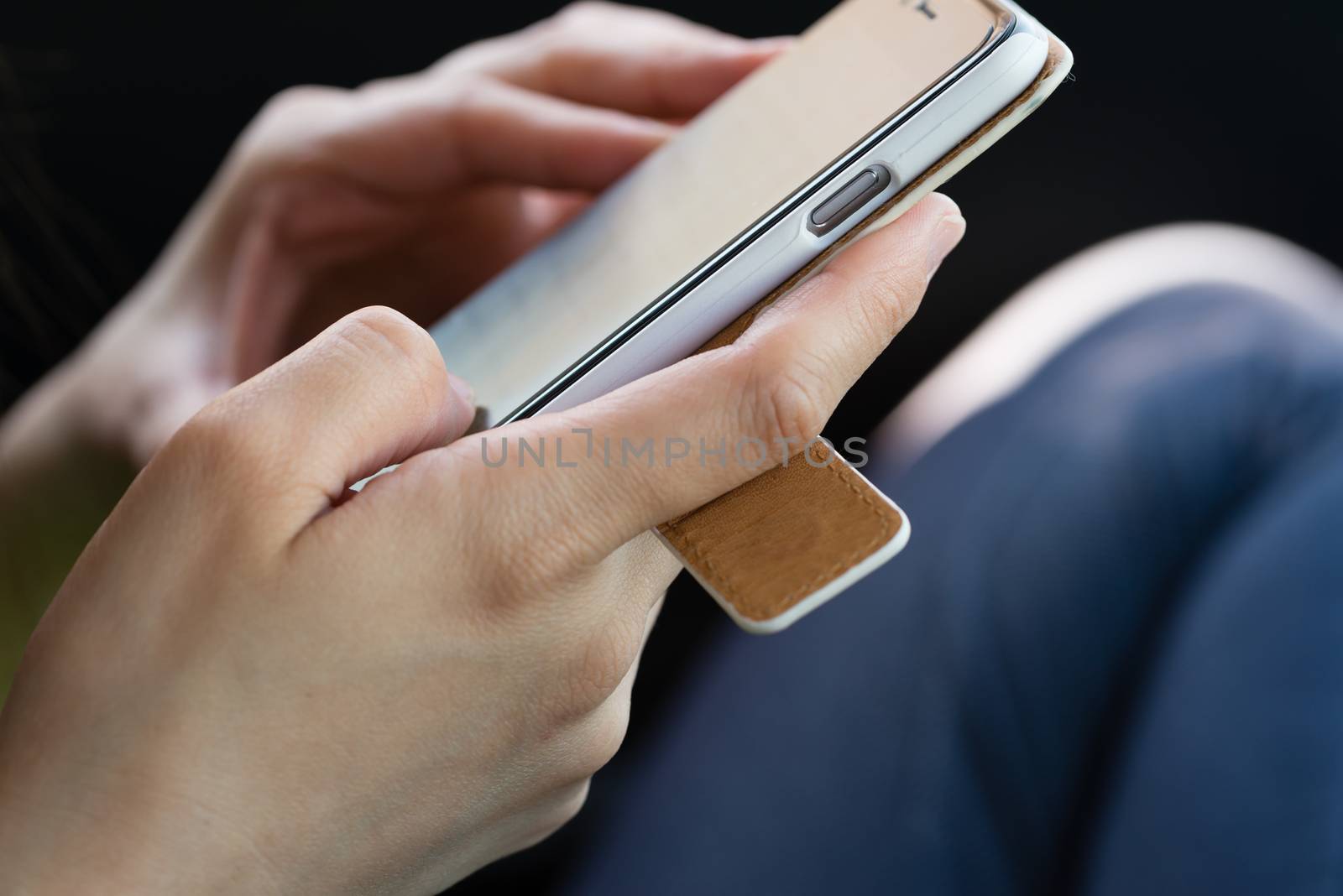 A close up of a girl's hands using a smartphone with a cover.