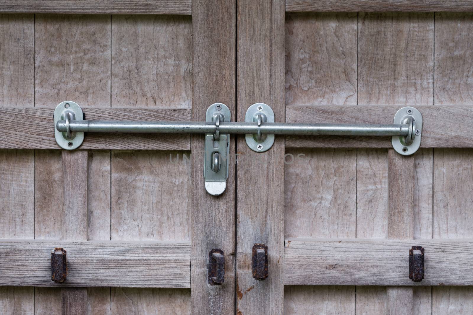 An old wooden door with rusty old locks and newer silver locks
