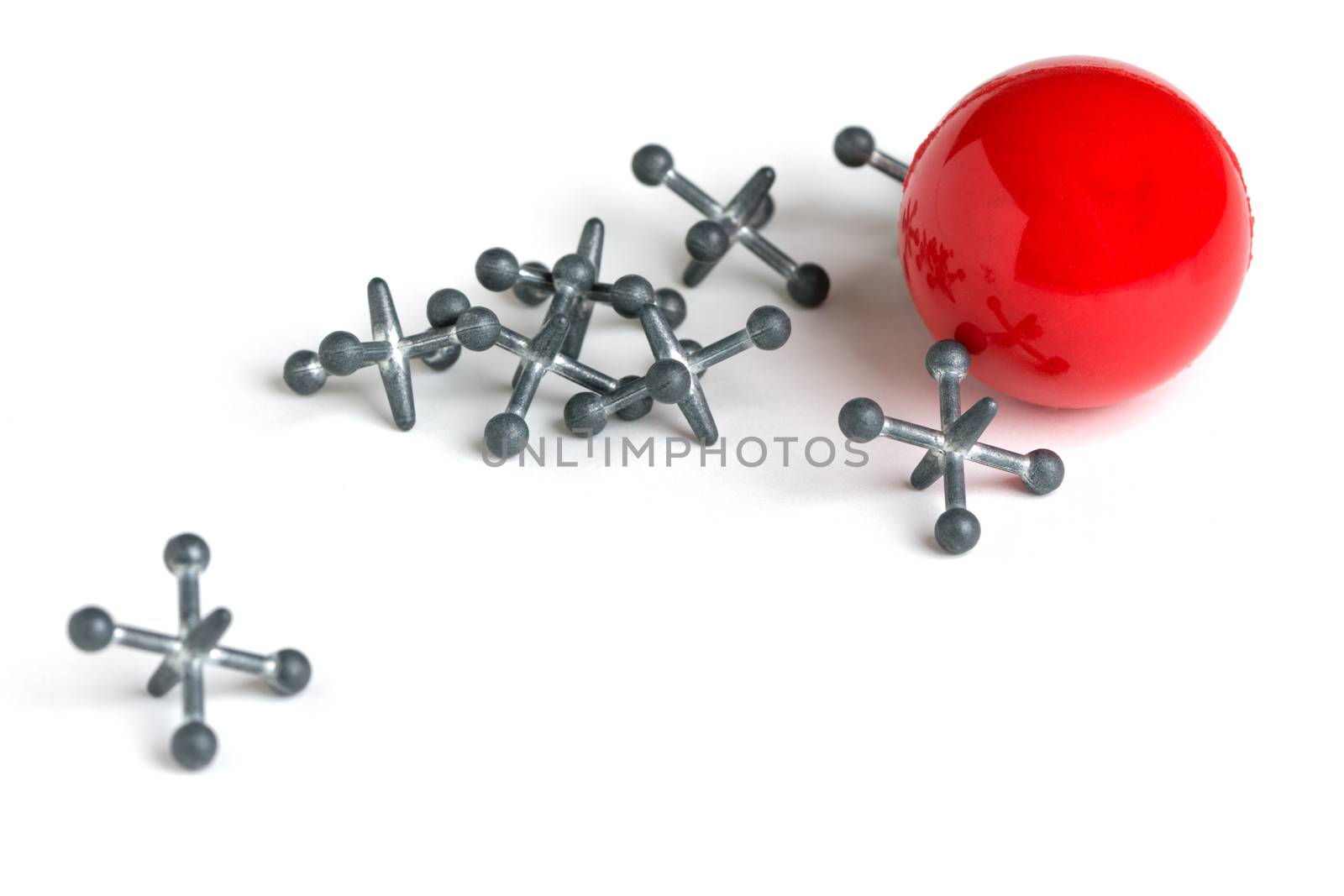A set of metal jacks and a red rubber ball isolated on a white background.