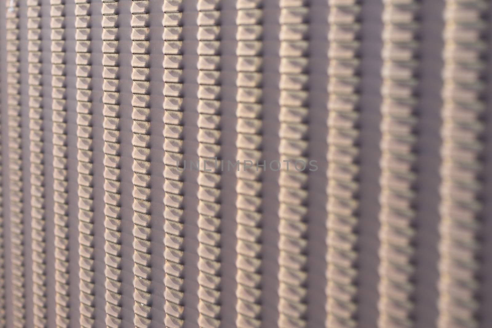 An abstract shot of a brown bumpy metal fence.