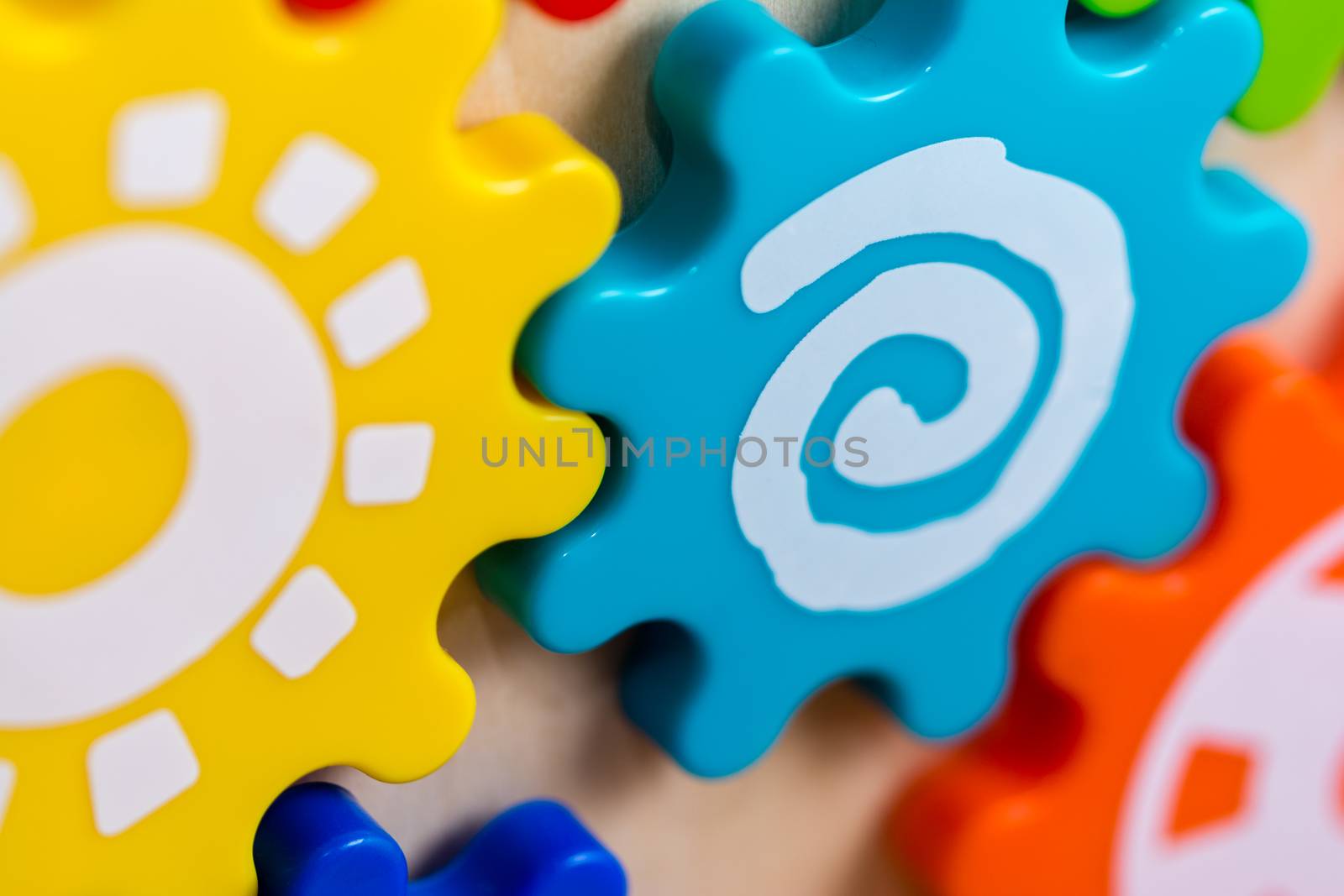 Colorful plastic gears on a children's toy with different white designs.