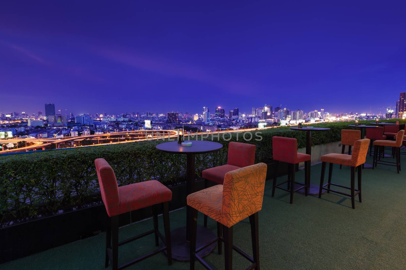 Restaurant dining table and view of business building on terrace at twilight evening time