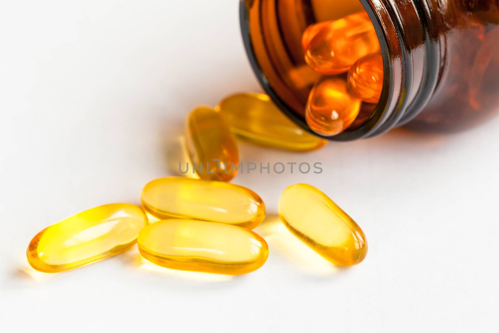 Yellow pills and bottle on white background close up