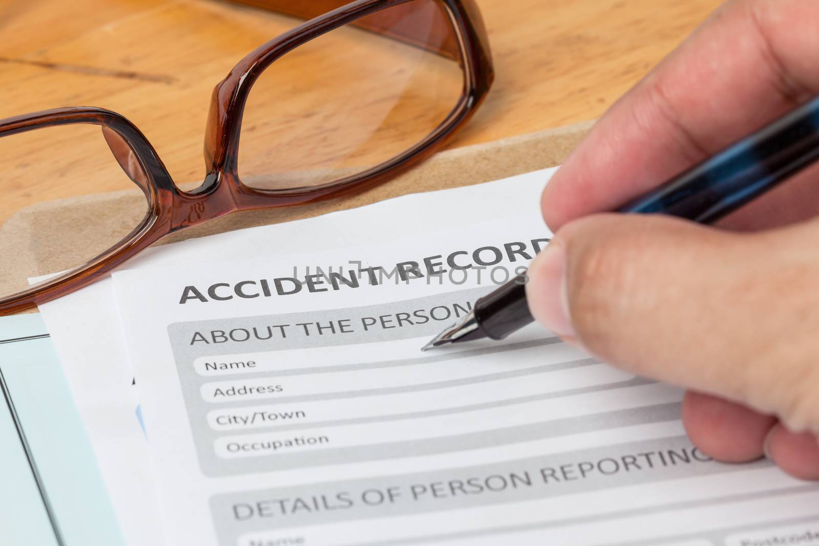 Accident report application form and human hand with pen on brown envelope and eyeglass, business insurance and risk concept; document is mock-up