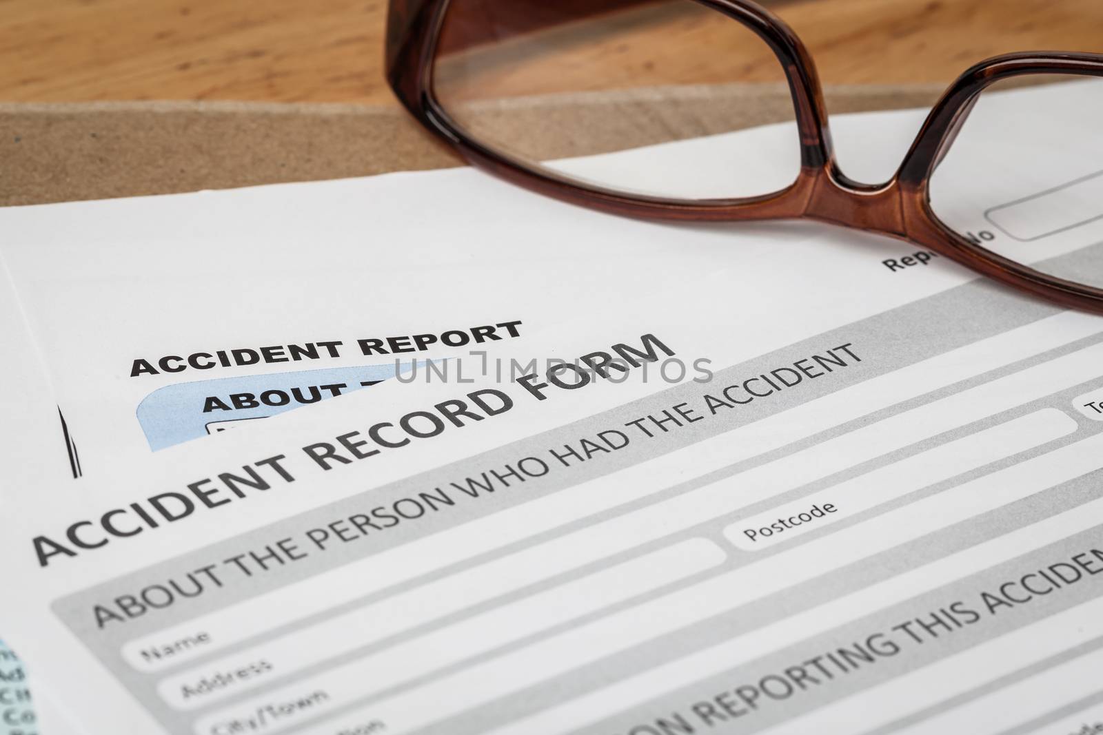 Accident report application form on brown envelope and eyeglass, business insurance and risk concept; document is mock-up