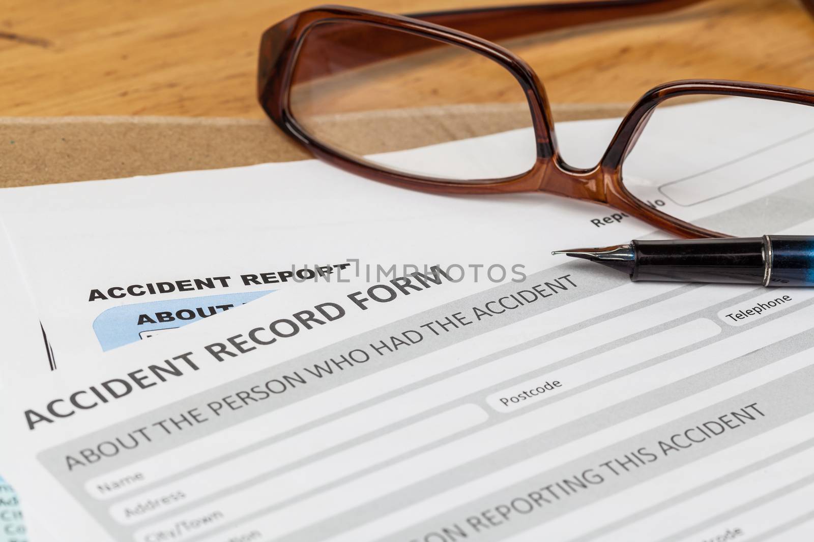 Accident report application form and pen on brown envelope and eyeglass, business insurance and risk concept; document is mock-up