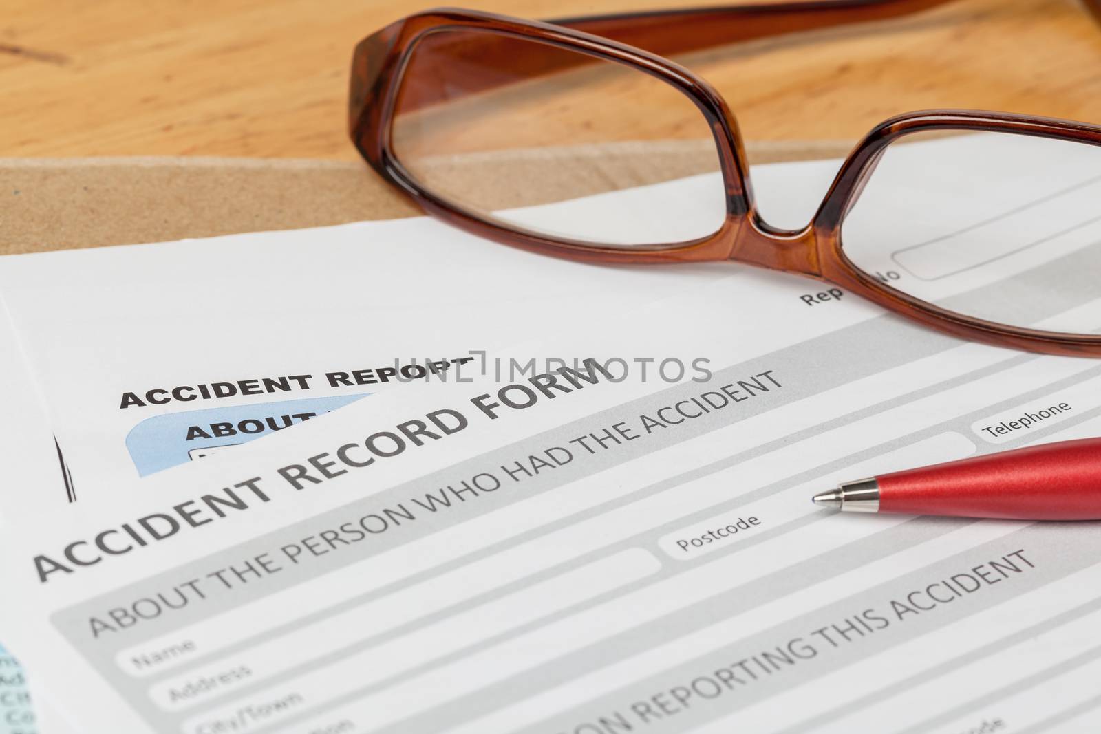 Accident report application form and pen on brown envelope and eyeglass, business insurance and risk concept; document is mock-up