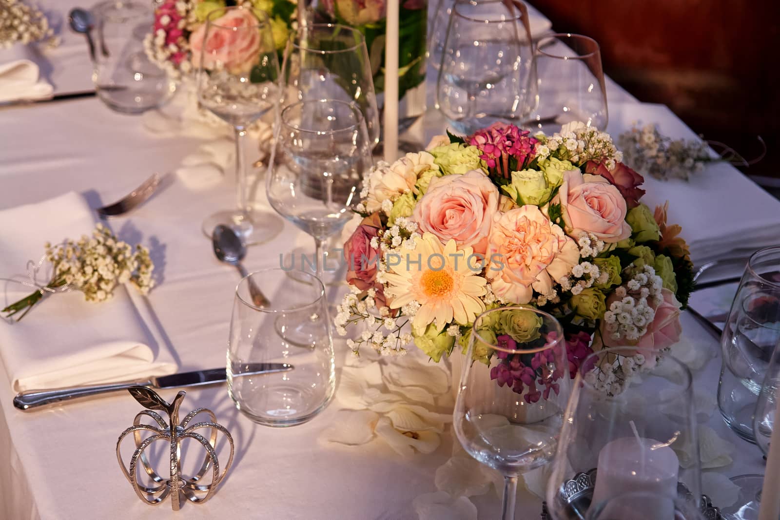 Festive wedding table setting with flowers, napkins, silver cutlery, glasses and candles                       