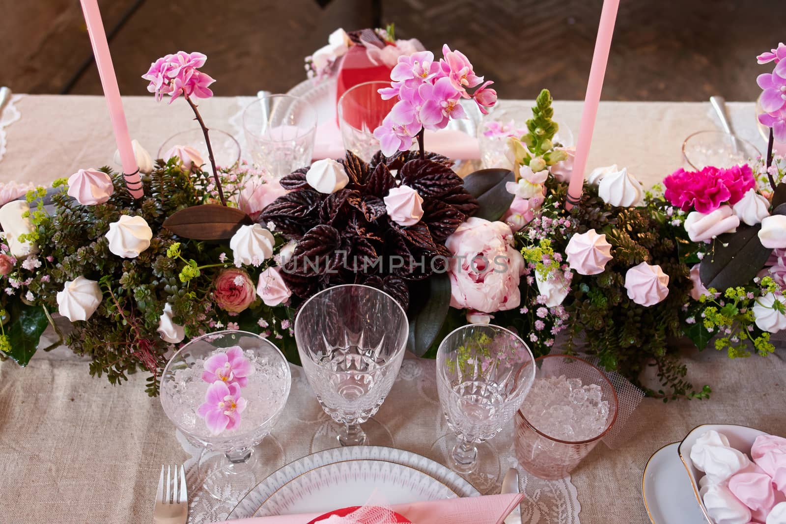 Festive wedding table setting with flowers, napkins, silver cutlery, glasses and candles