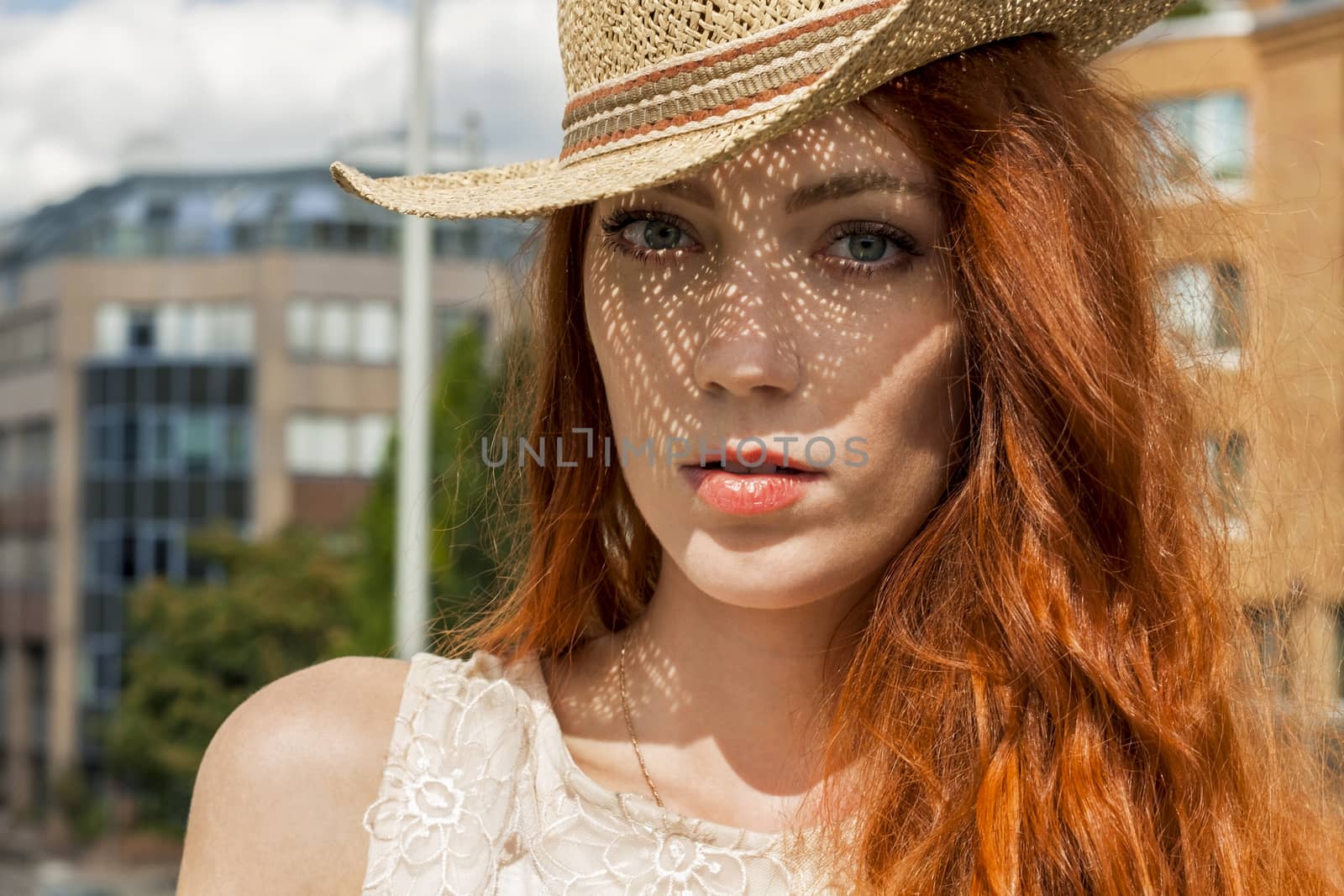 Gorgeous Woman in Hat with red hair on Cloudy Sky background