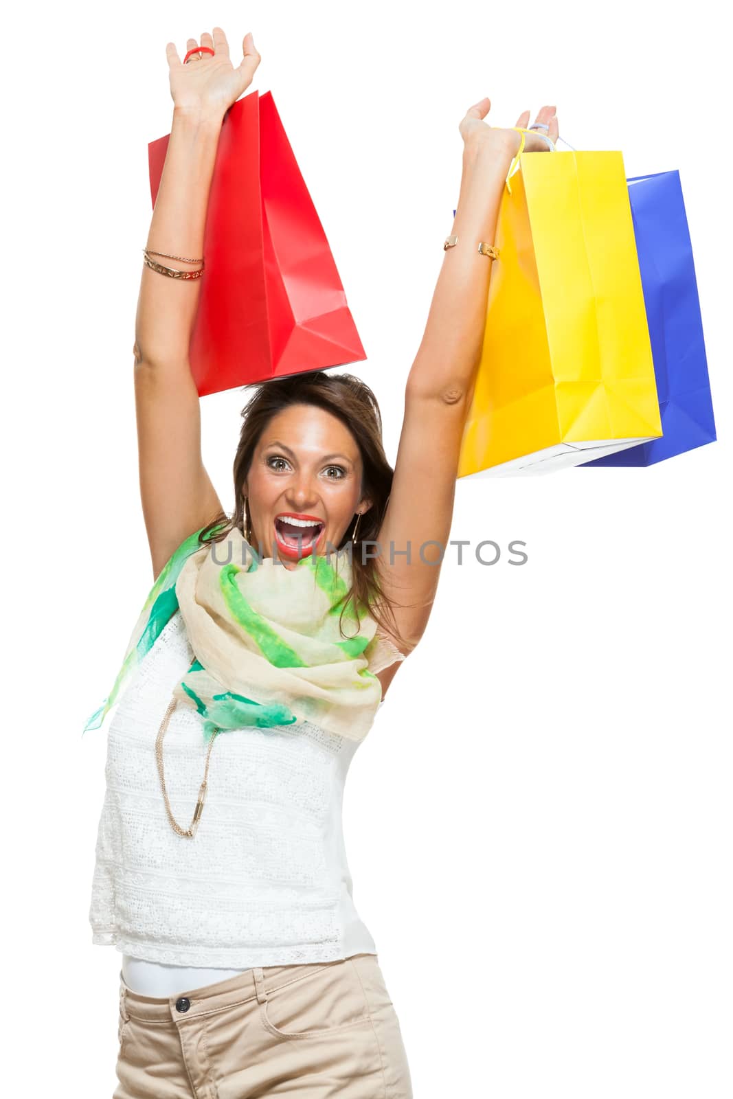 Very Happy Stylish Woman Raising Three Colored Shopping Paper Bag with Mouth Open and Looking at the Camera. Isolated on White Background.