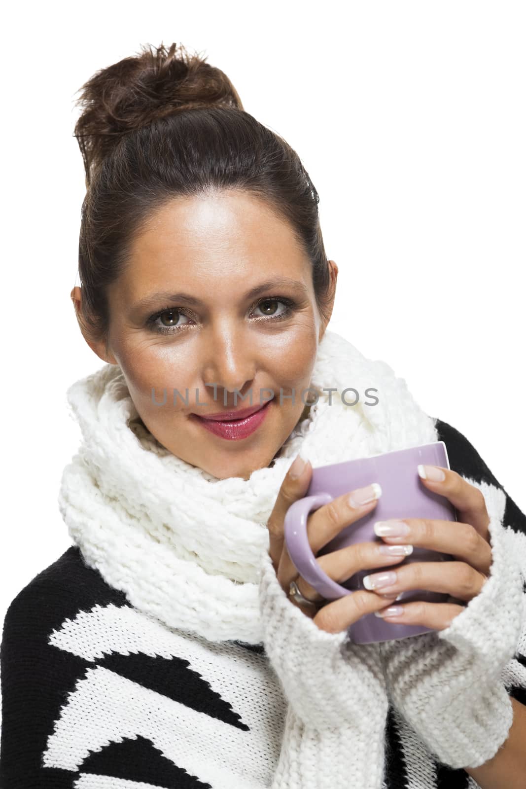 Cold attractive stylish woman in an elegant black and white winter outfit clasping a mug of hot coffee in her hands while savoring the aroma with a look of anticipation