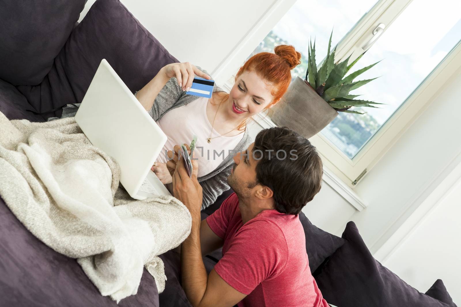 Close up Young Couple Resting at the Couch with Laptop Computer, ATM Card and Euro Cash.