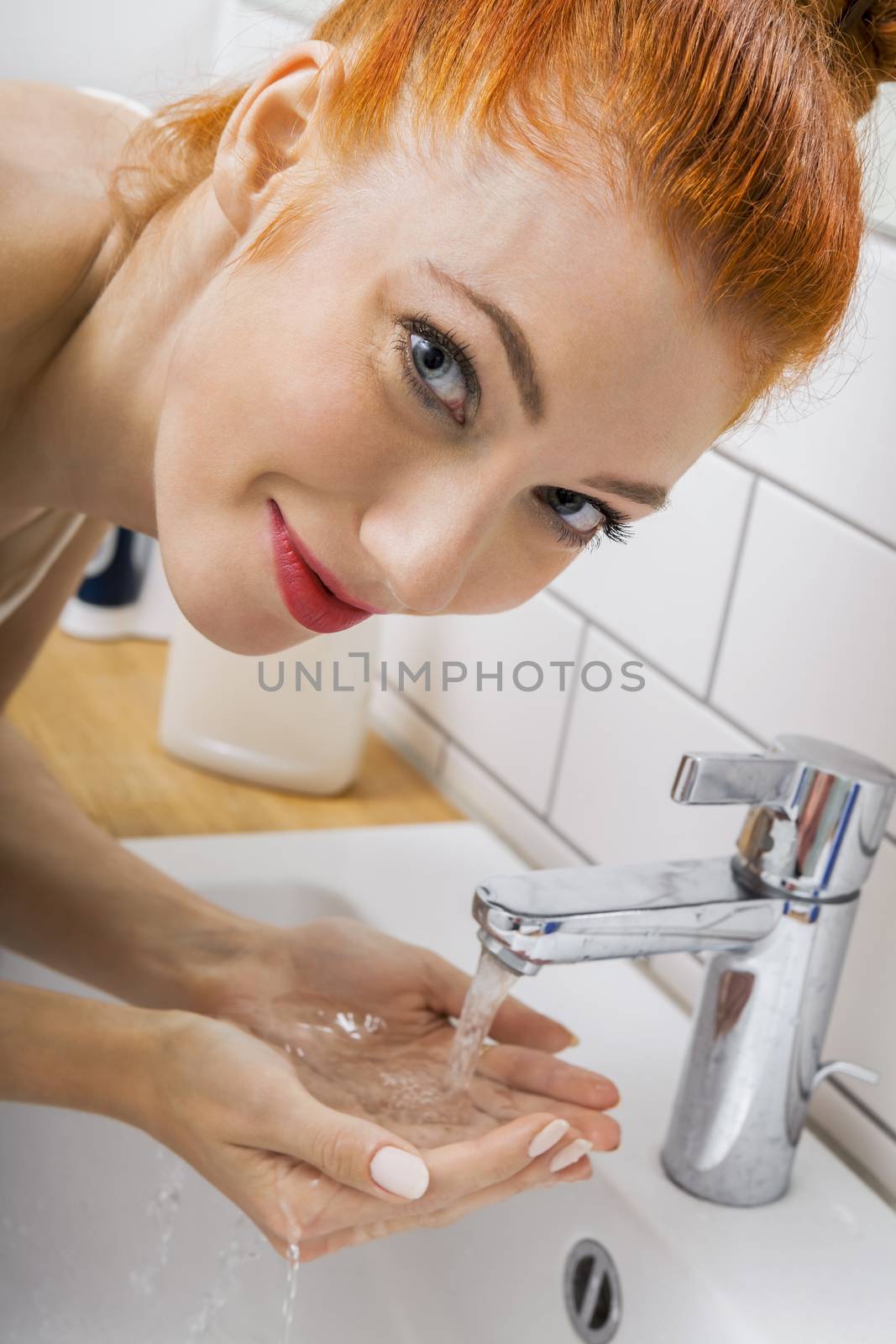 Close up Happy Young Woman Washing her Face While Looking at the Camera for a Moment.