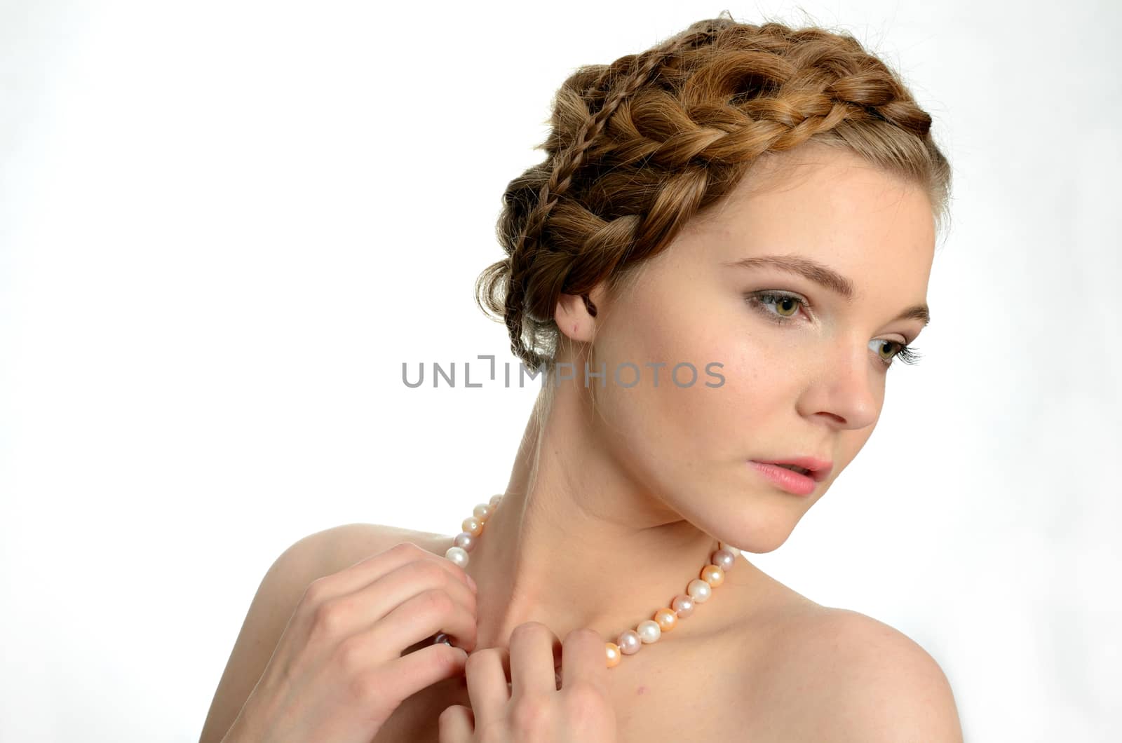 Portrait of young girl, kind face expression. Girl wears pearls and holds them by hands.