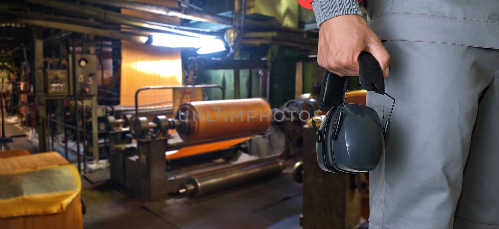 Worker with protective headphone at man hands at industrial factory