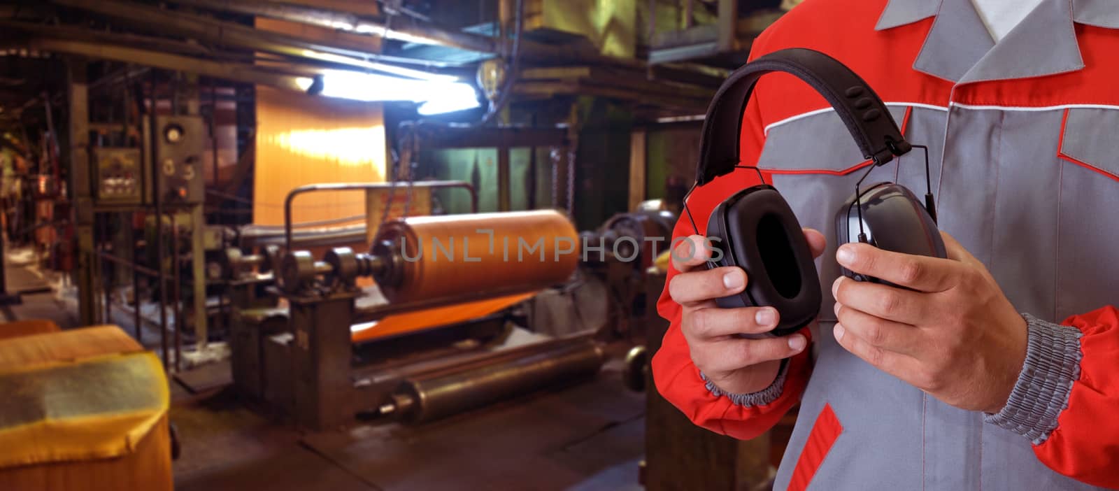 Worker with protective headphone at man hands at industrial factory