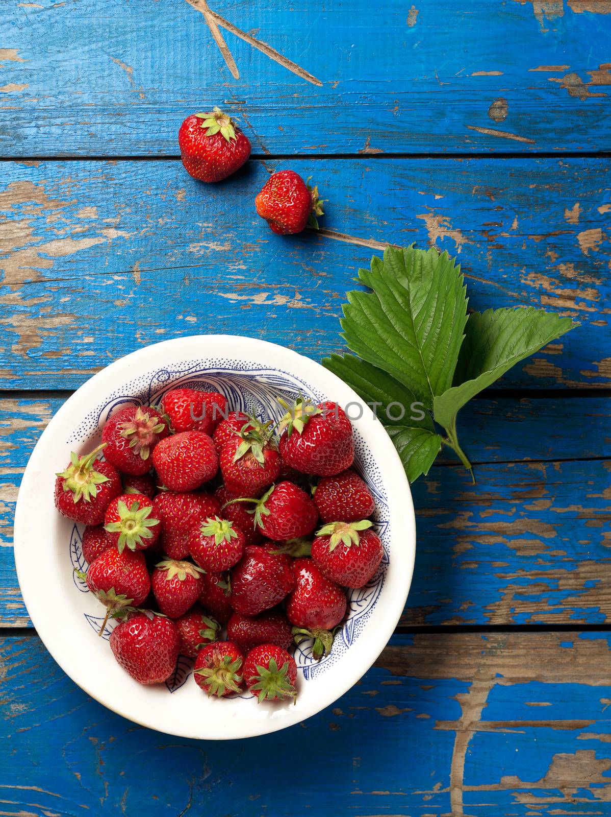 Fresh and ripe strawberries plate on the blue table