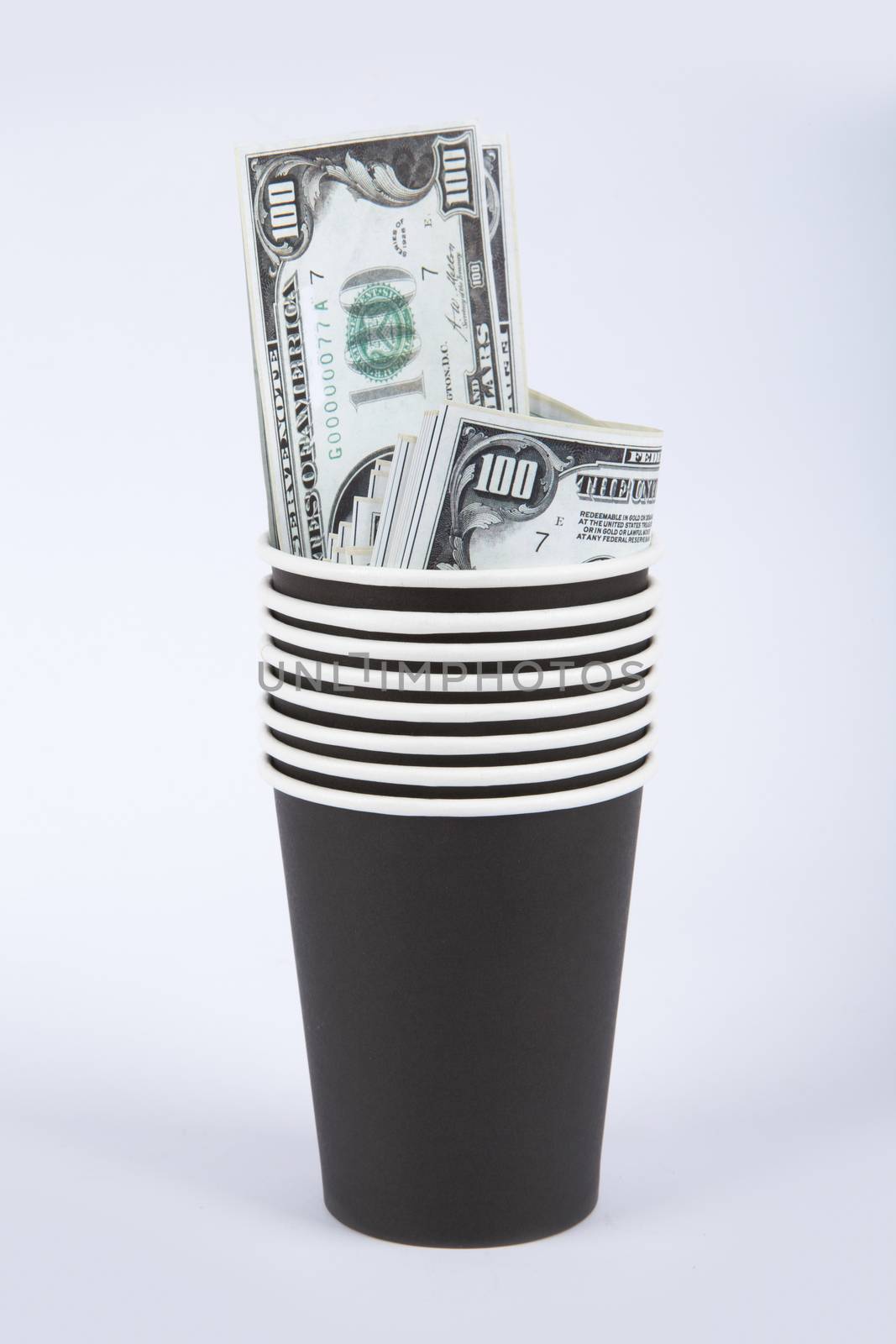 Close up front view of black paper glasses with banknotes of one hundred dollar inside, isolated on white background.