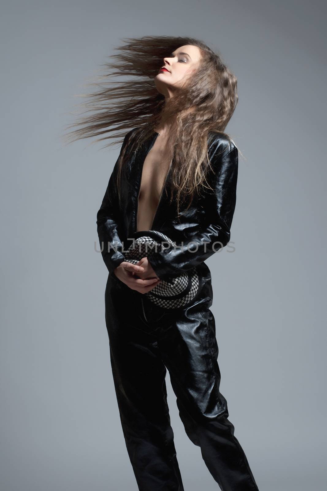 Woman in Leather Dress Holding a Hat and Hair Flying