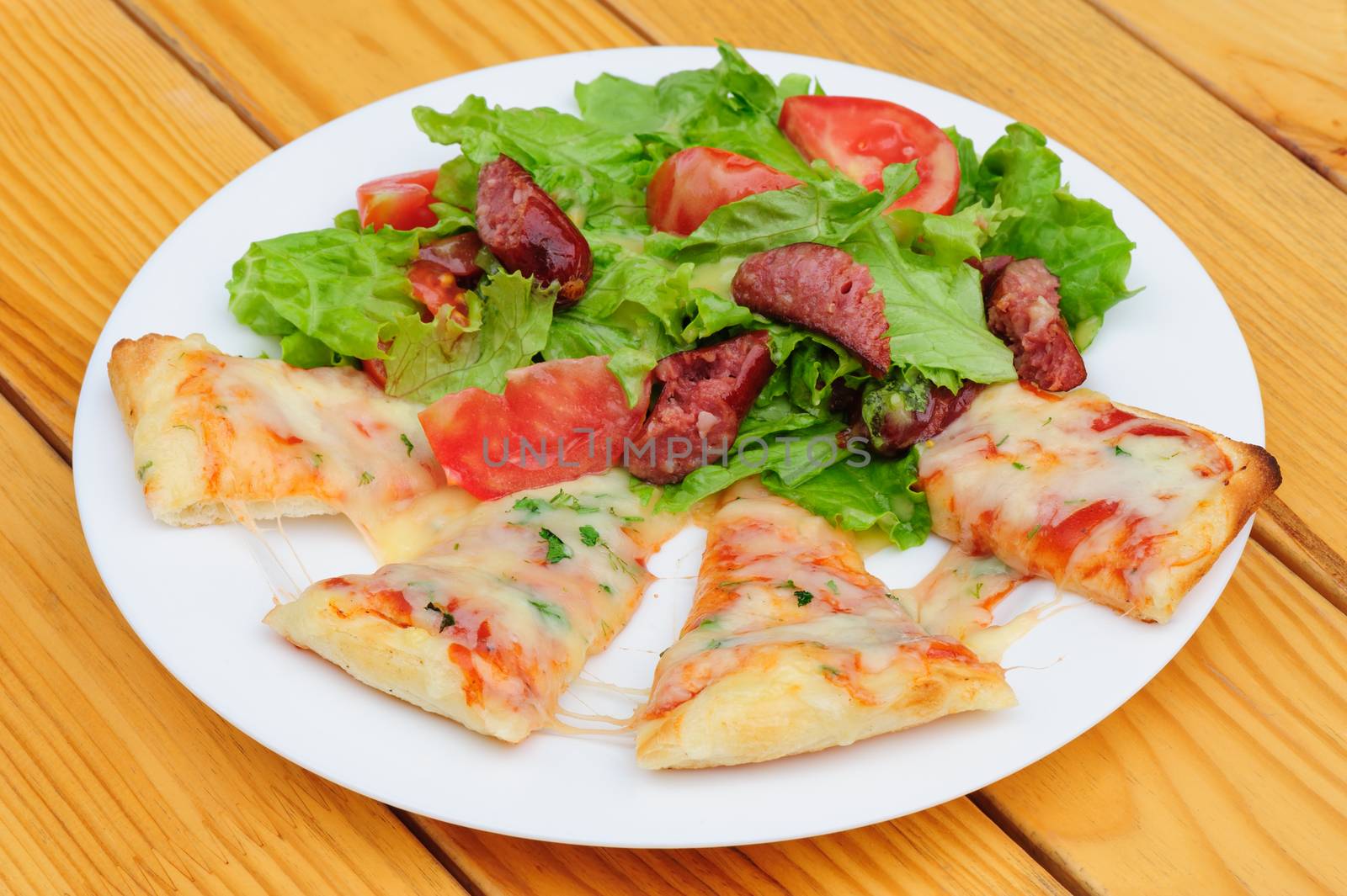 Pizza slices with melted cheese and fresh vegetables salad
