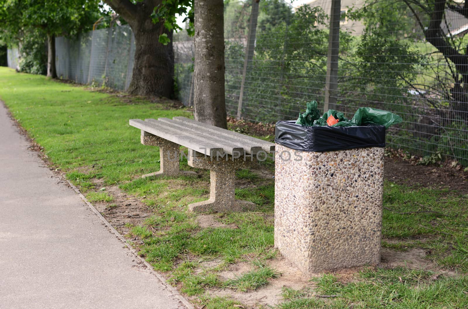 A full rubbish bin makes an empty bench an unwelcoming place to rest