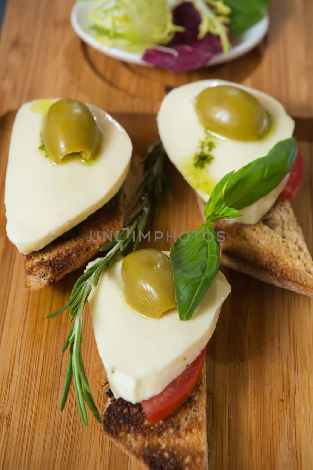 Bruschetta with tomato, mozarella and olive on wooden table 