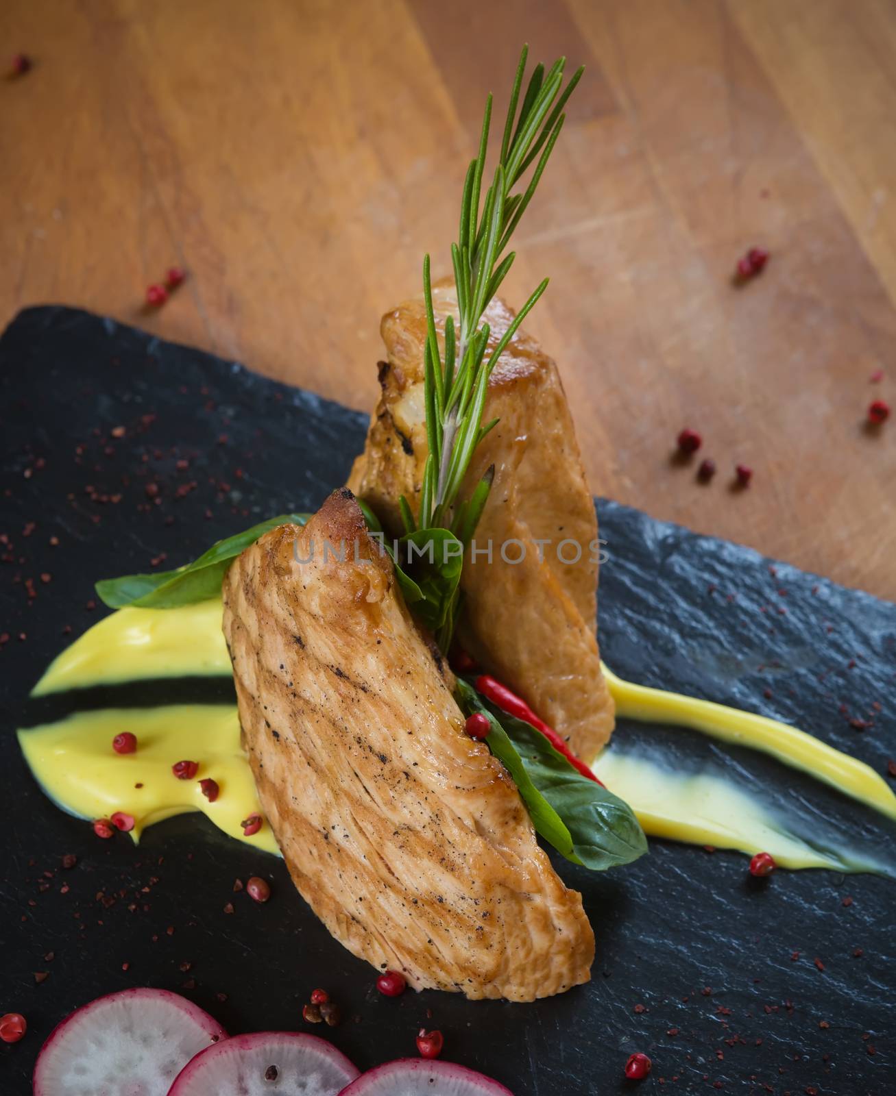 Grilled turkey steak on black board and brown wooden background