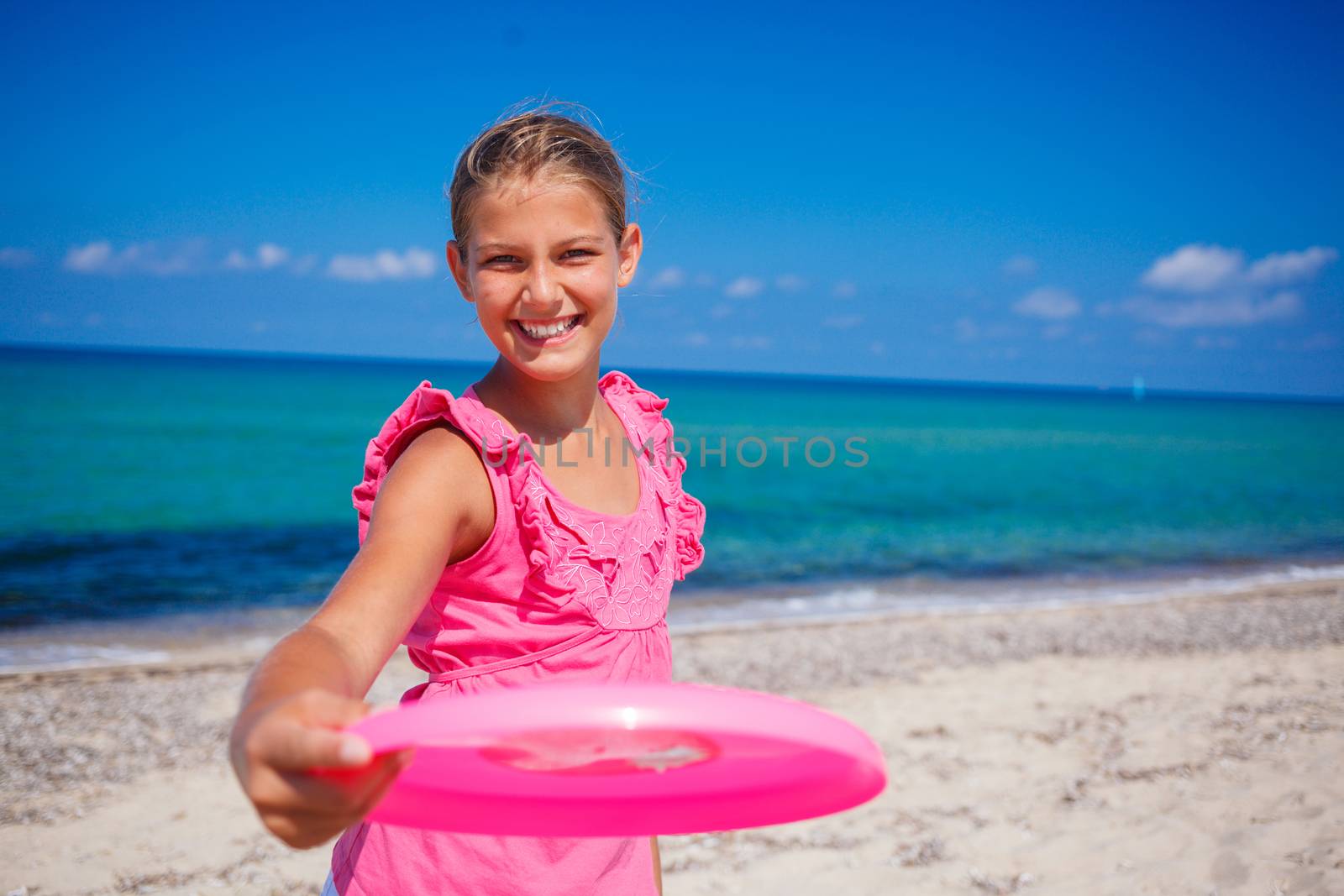 Happy cute girl playing frisbee on beach