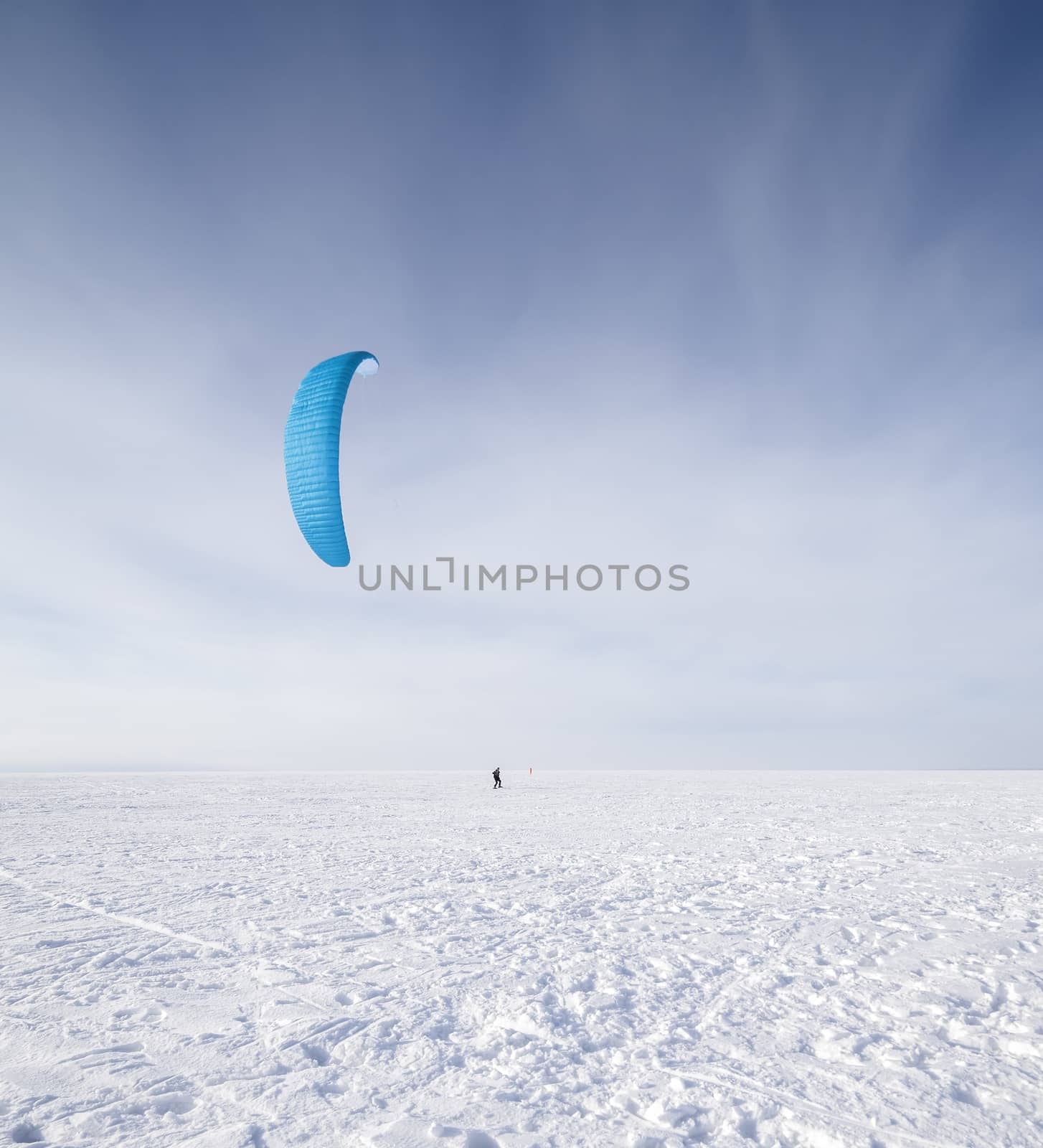 Kite surfer being pulled by his kite across the snow