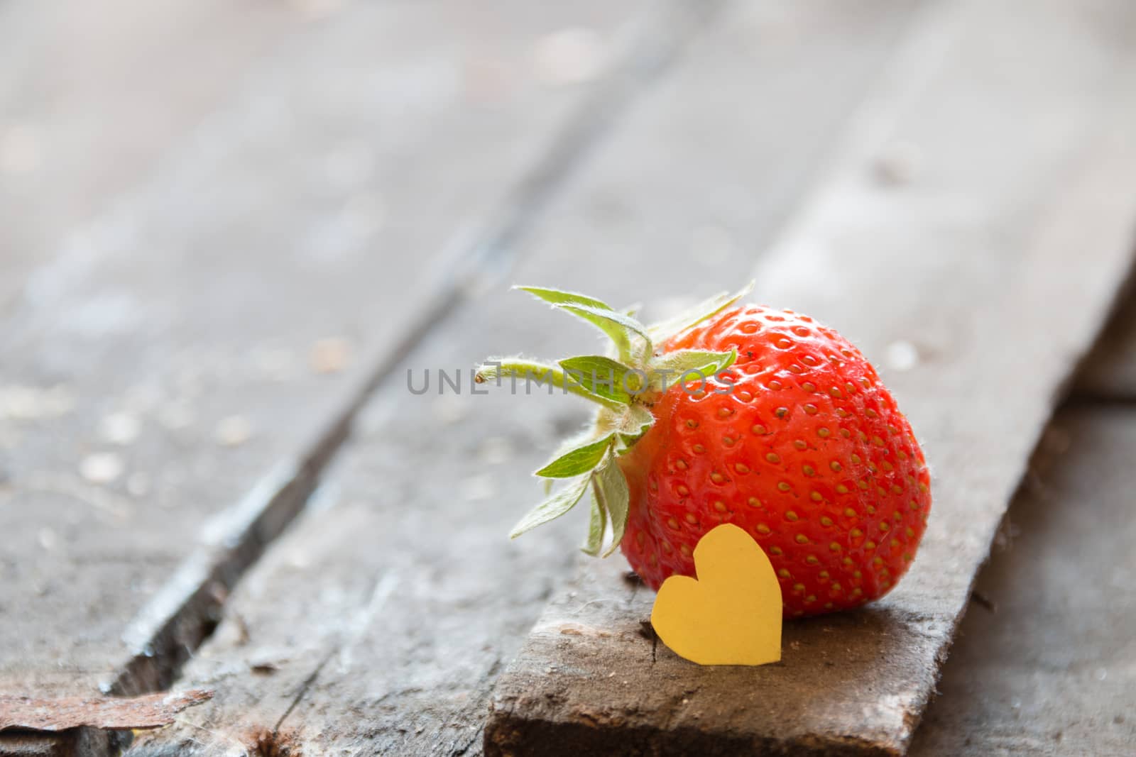 Cooking with love idea. Strawberry and paper heart on a wooden table.