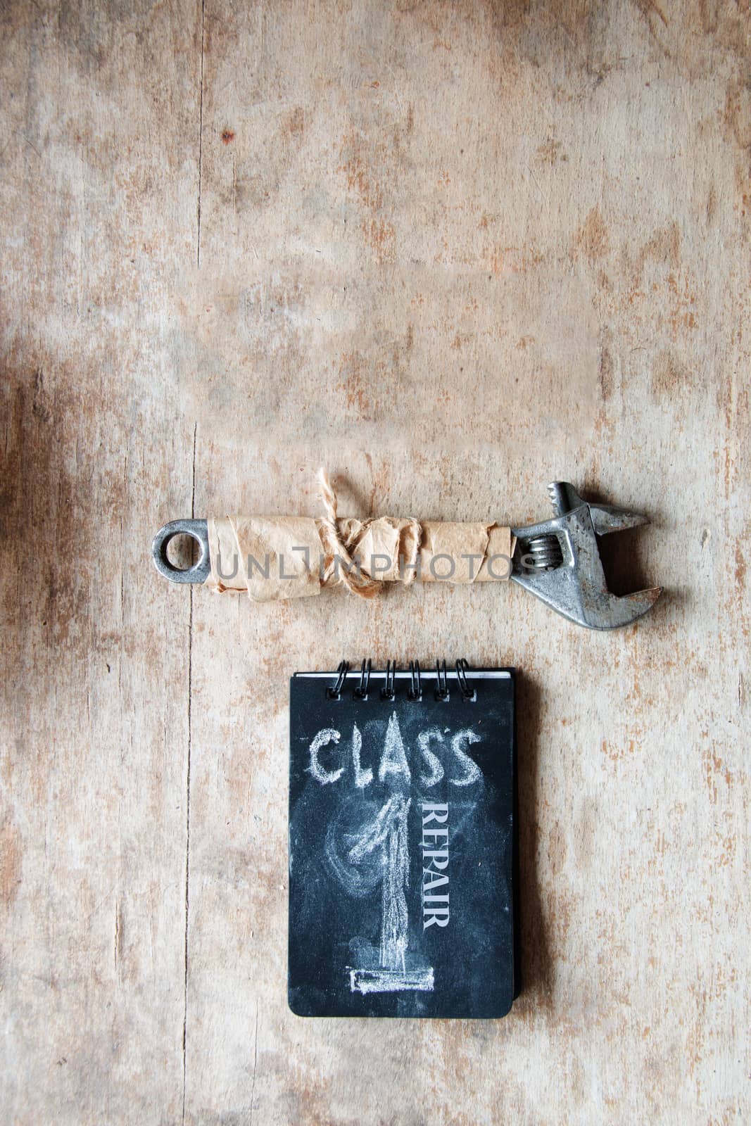 Repair concept. Inscription repair, first class and a wrench on a wooden table workshop.