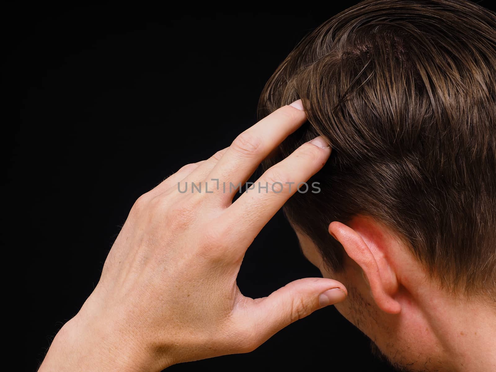 Closeup of a caucasian male thinking with one hand towards head isolated on black