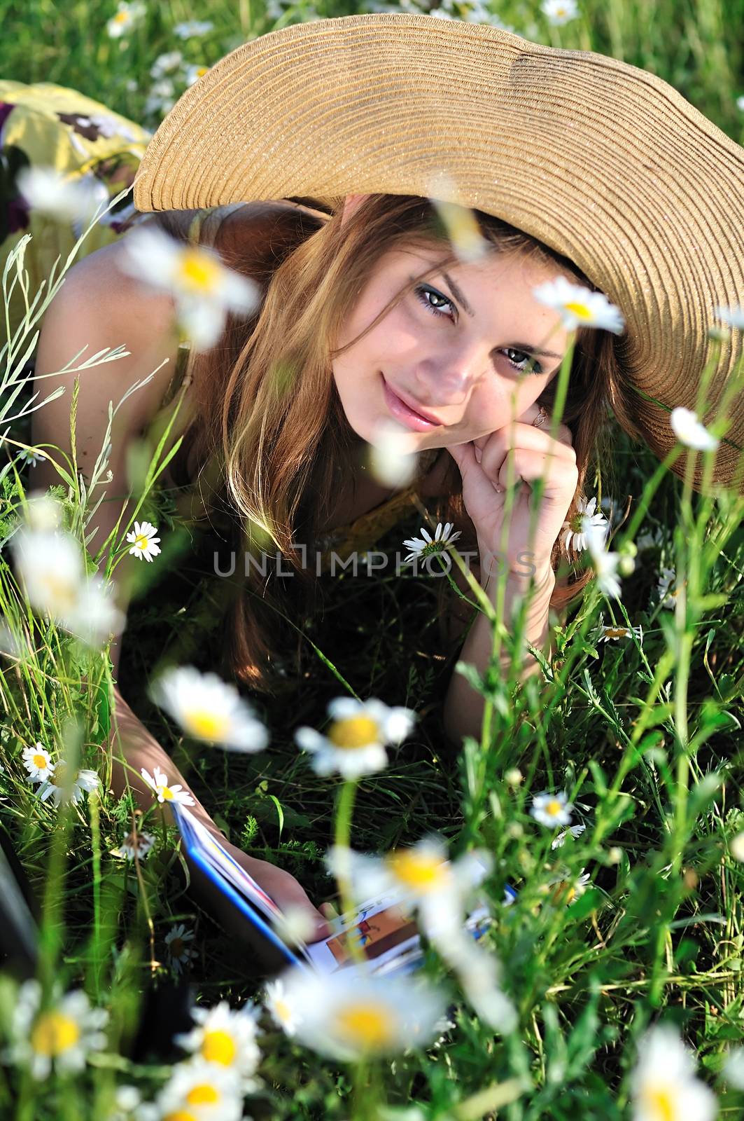 teen girl reading a book on the daisy meadow 