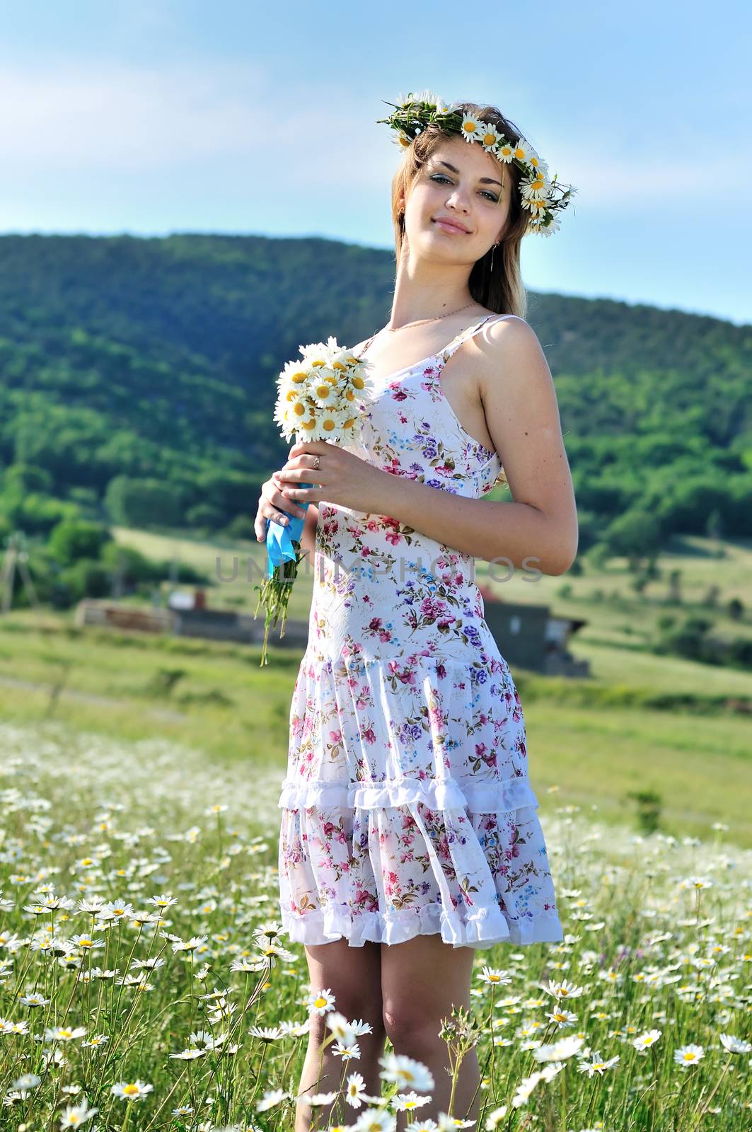 stunning spring lady standing in thr daisy field and holding bunch of flovers