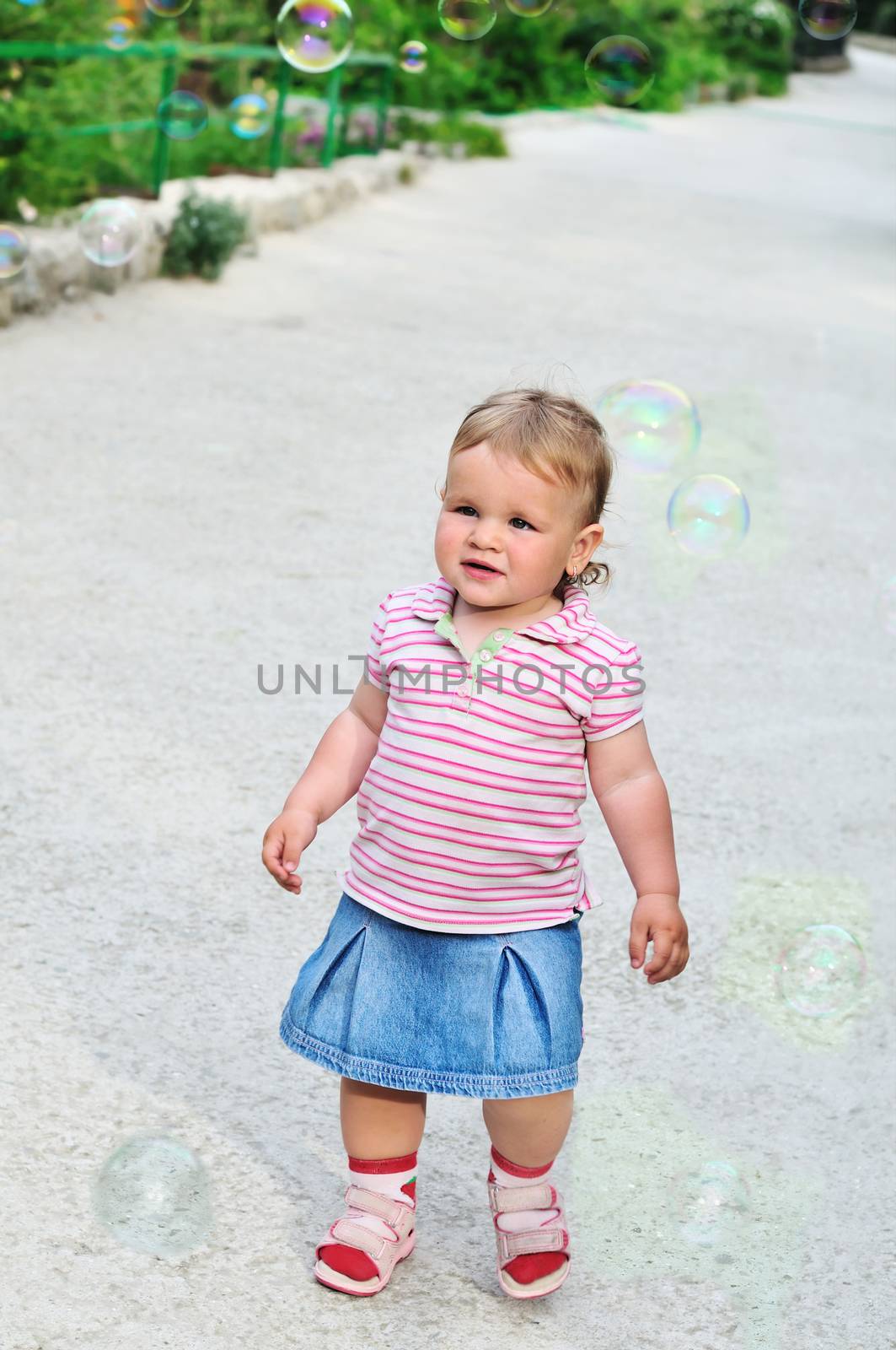 baby girl walking through soap bubbles in the park
