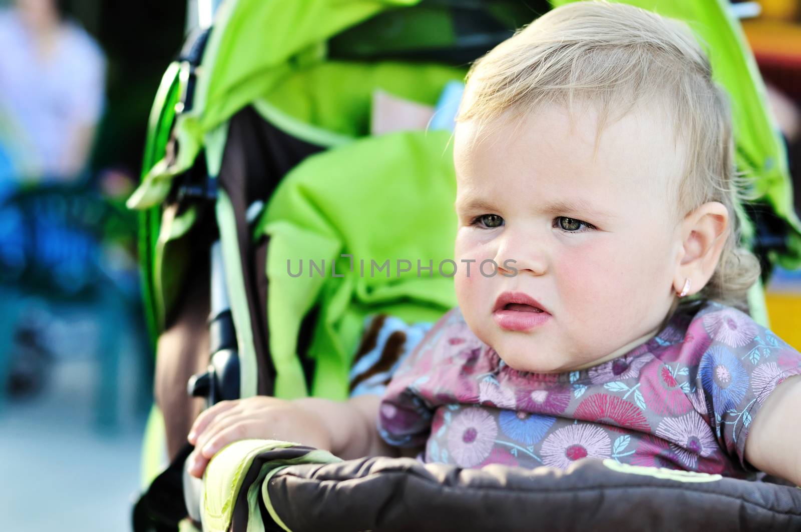 serious toddler girl sitting in the stroler