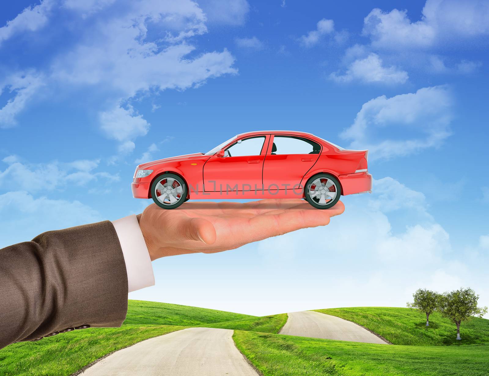 Car on businessmans right hand on blue sky background and green grass