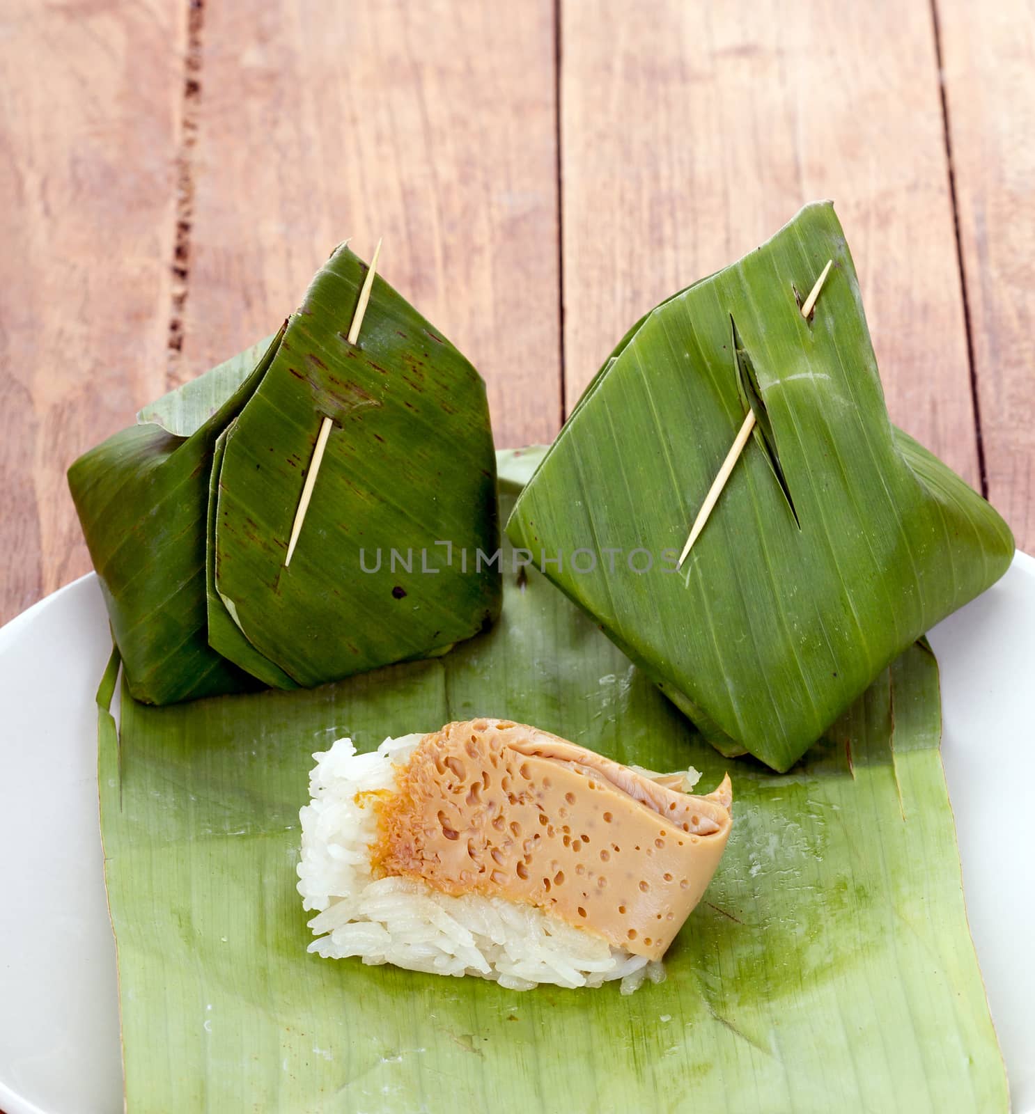 Thai Dessert - Sticky Rice with Egg Custard warpped by banana leaf on white dish