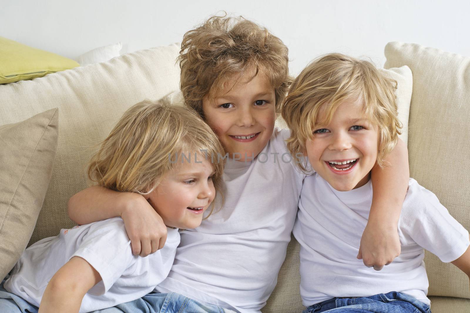 Three brothers hugging and playing on the sofa