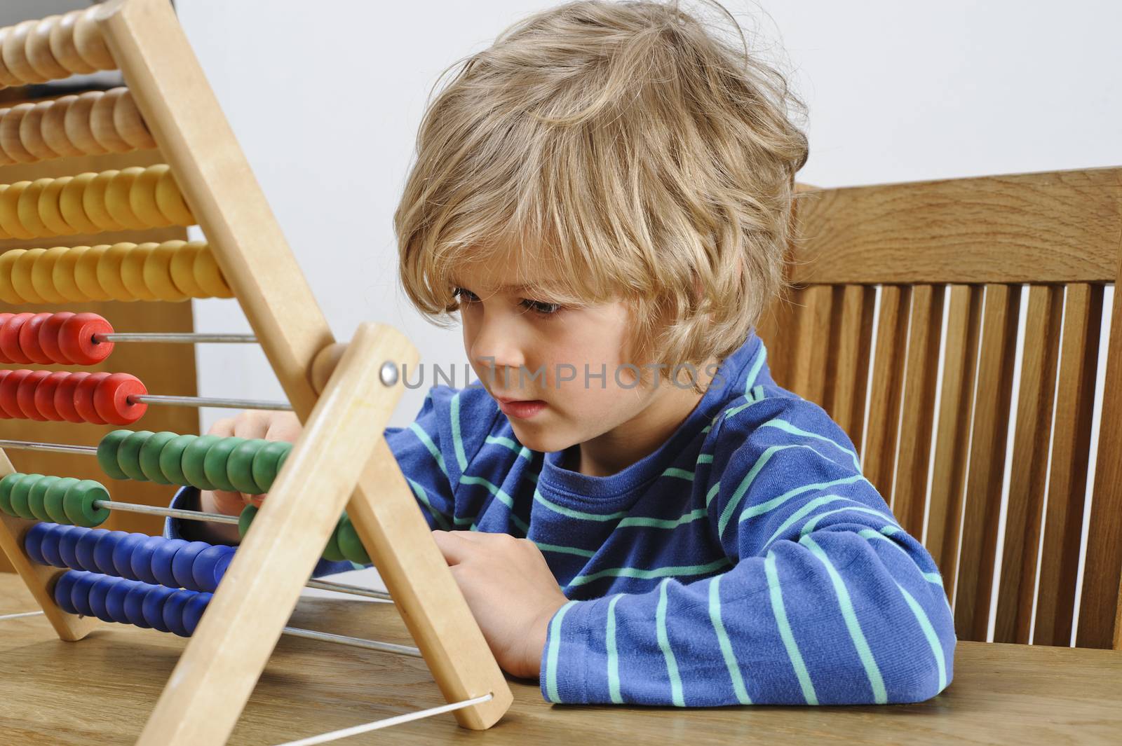 A young boy learns to count using an abacus