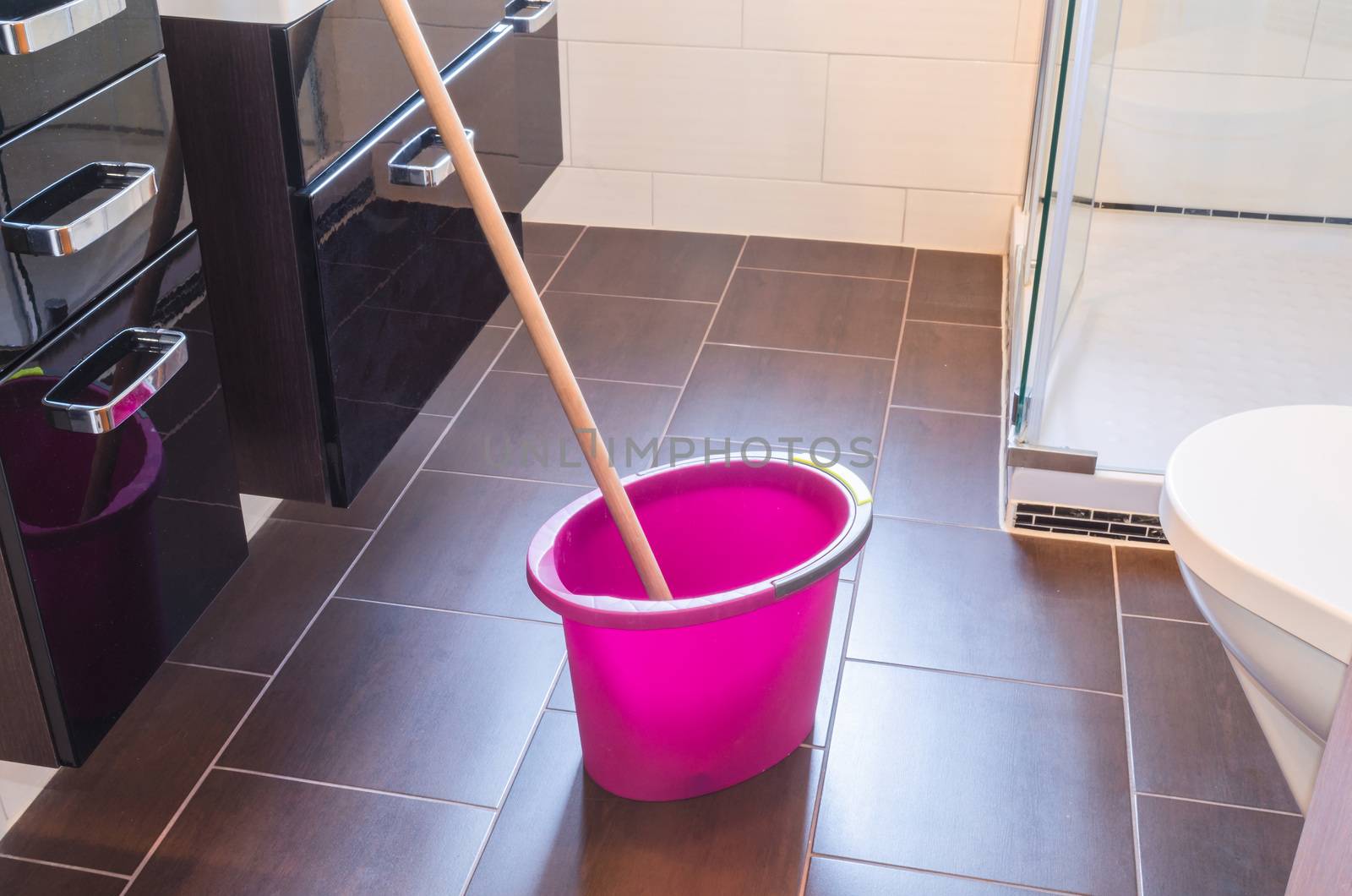 Spring cleaning bucket with mop on a tiled floor.