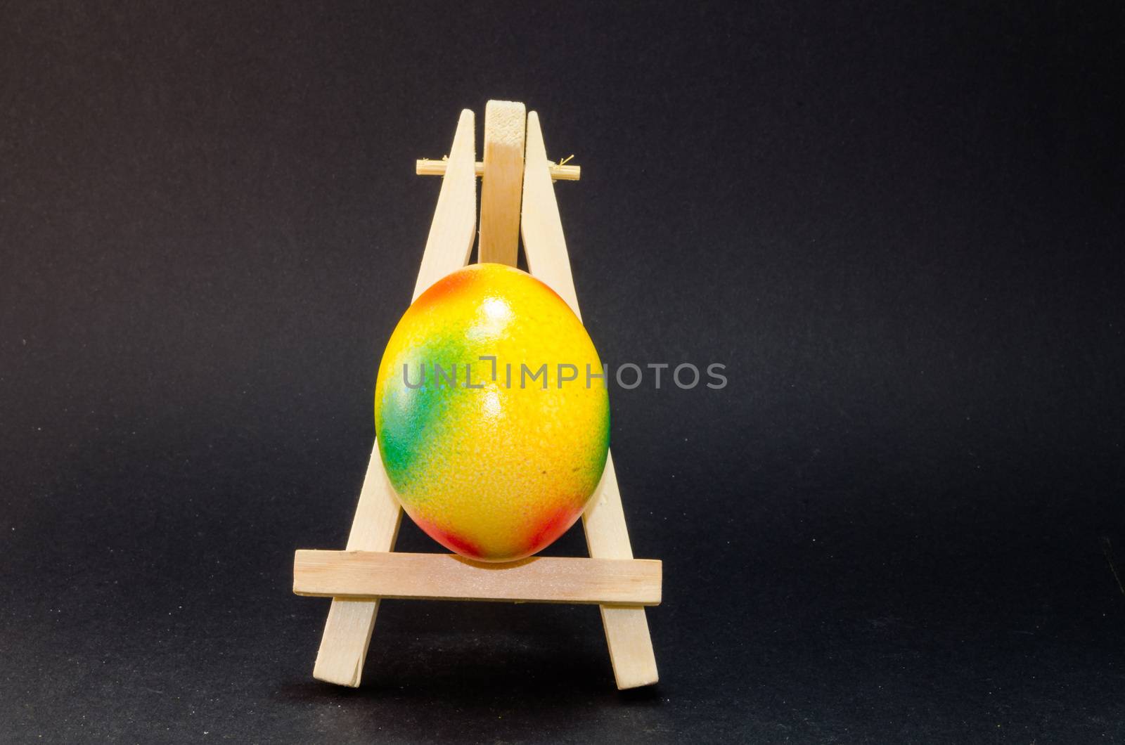Easter is on artist easel. Easter egg painting. black Background